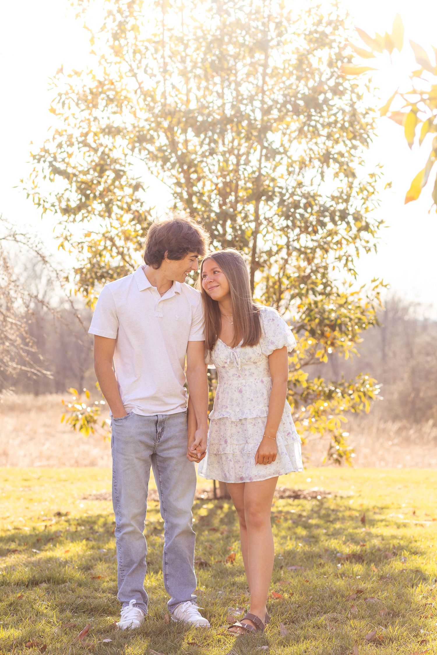 Couple standing together holding hands and smiling during park session