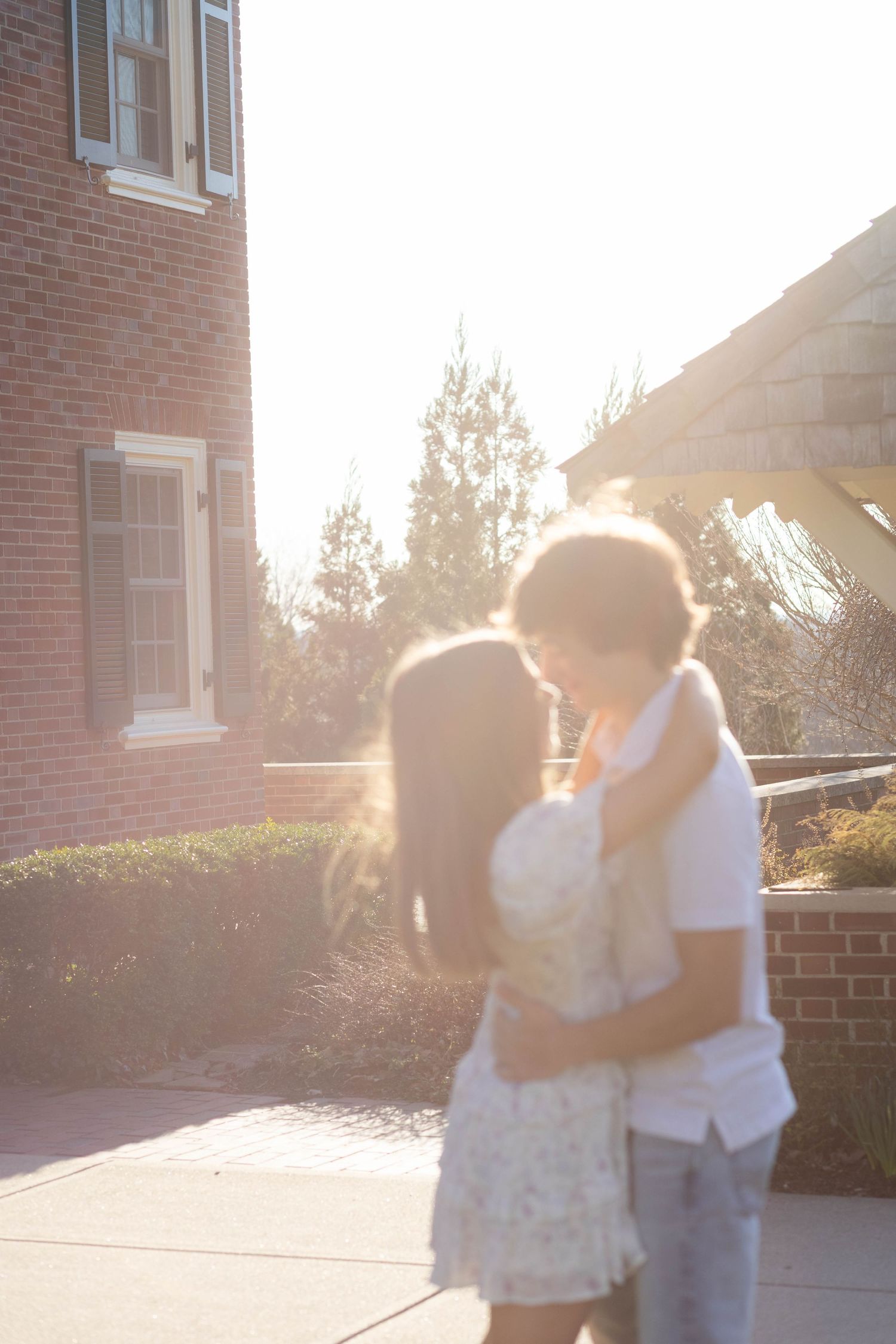 Candid couple photo embracing in front of brick building during sunset session