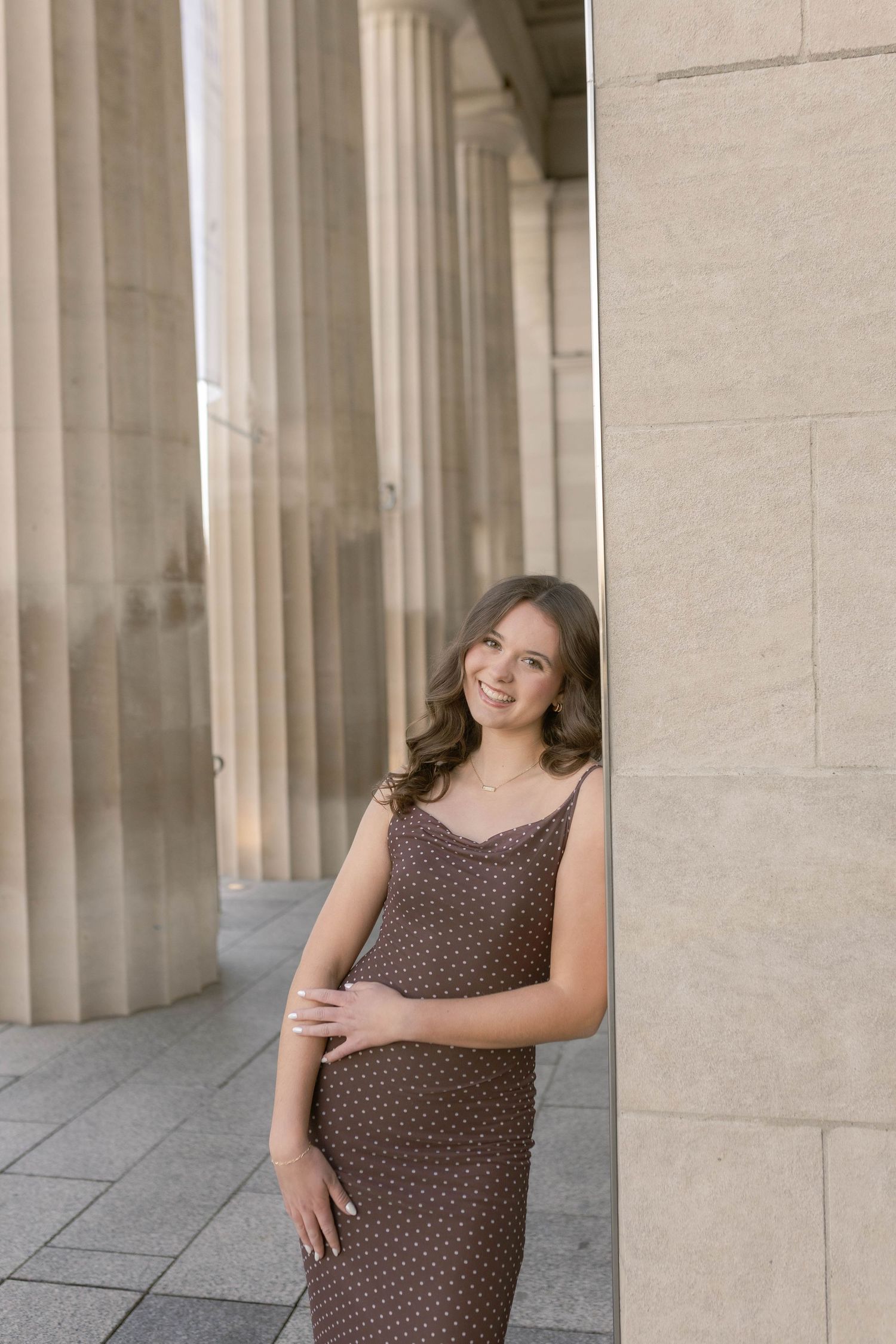 Girl standing and laughing against marble column at museum