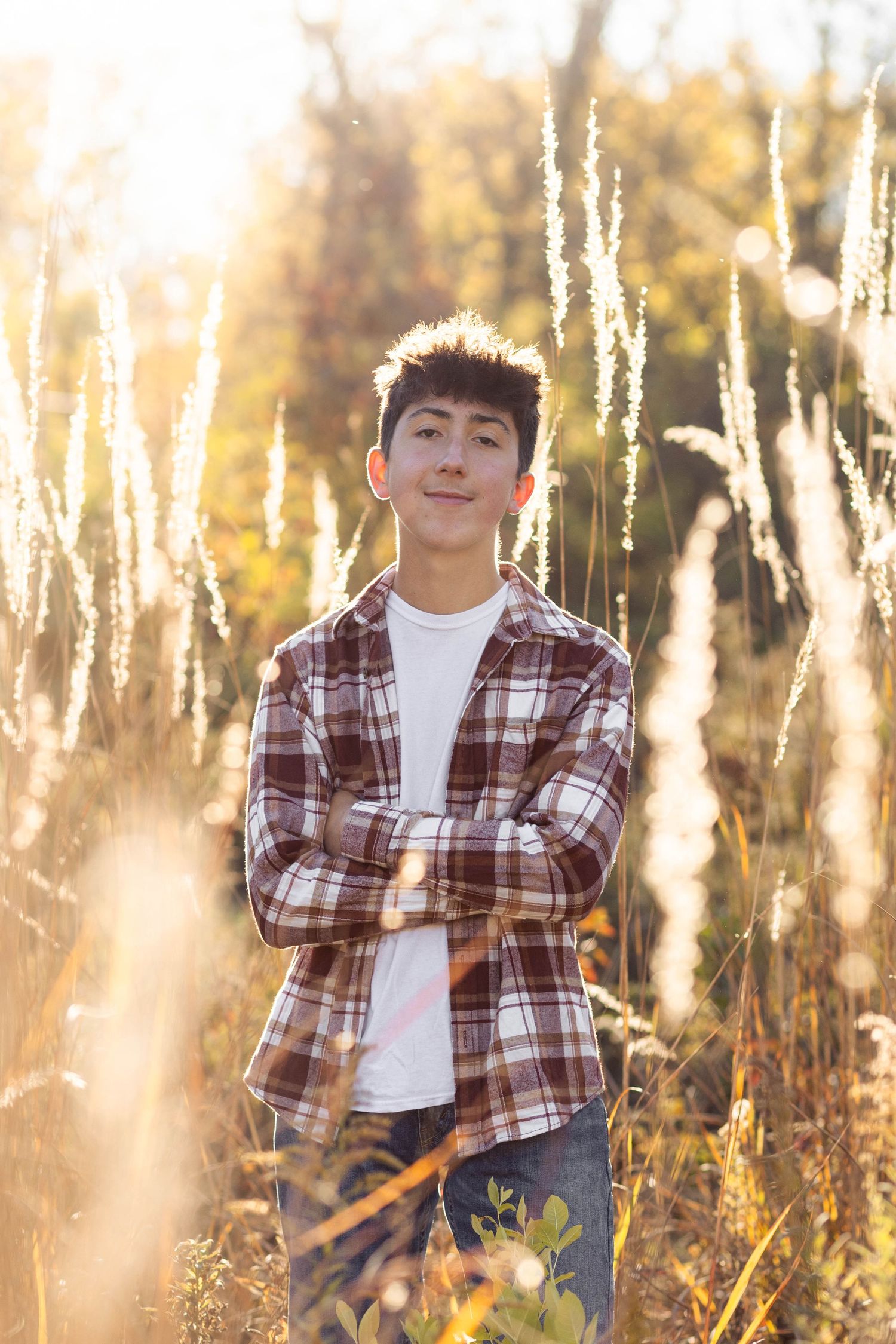 Teen boy posing in open field for senior pictures at golden hour
