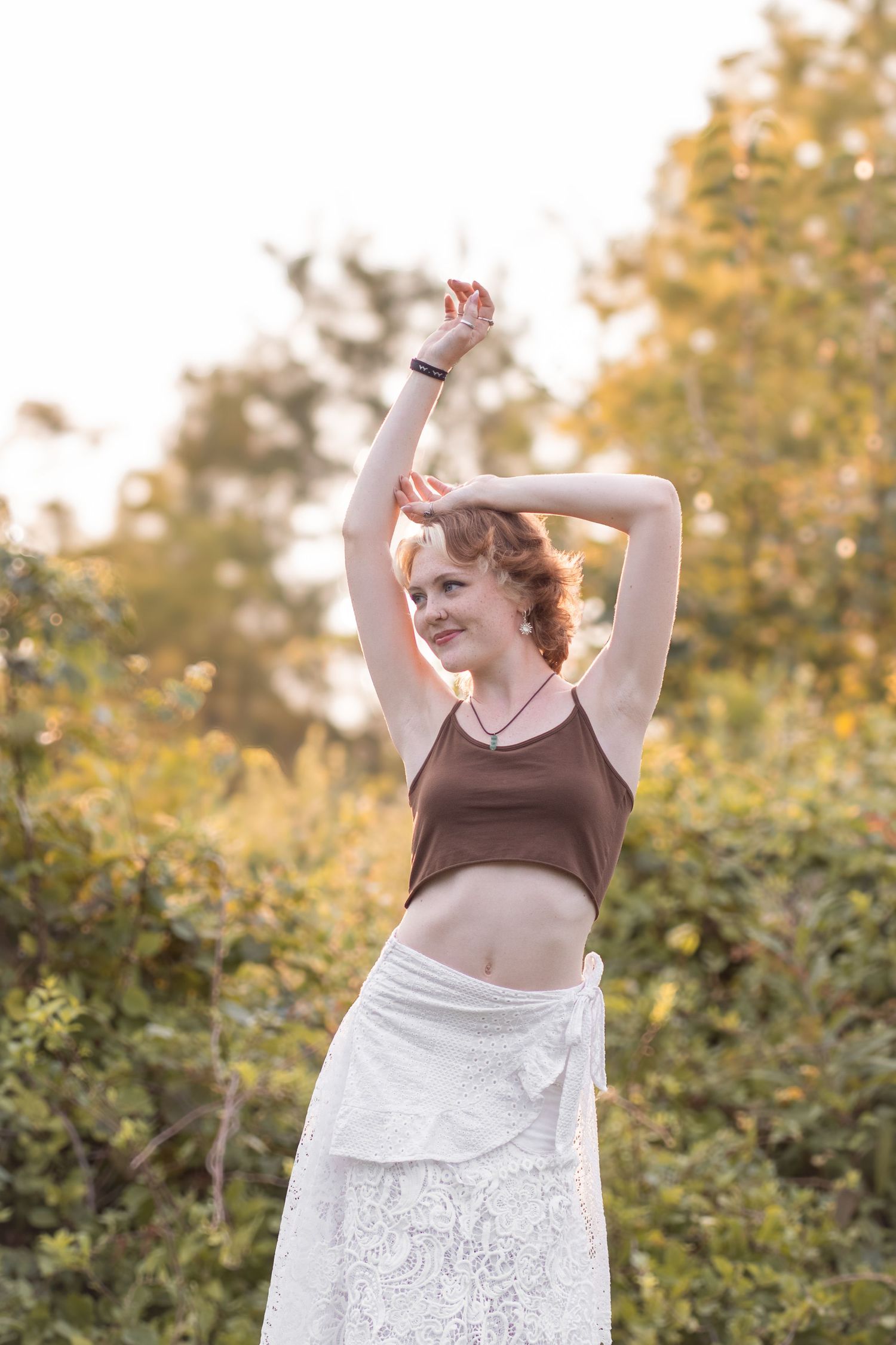 Outdoor senior portrait in grassy meadow with warm golden hour glow