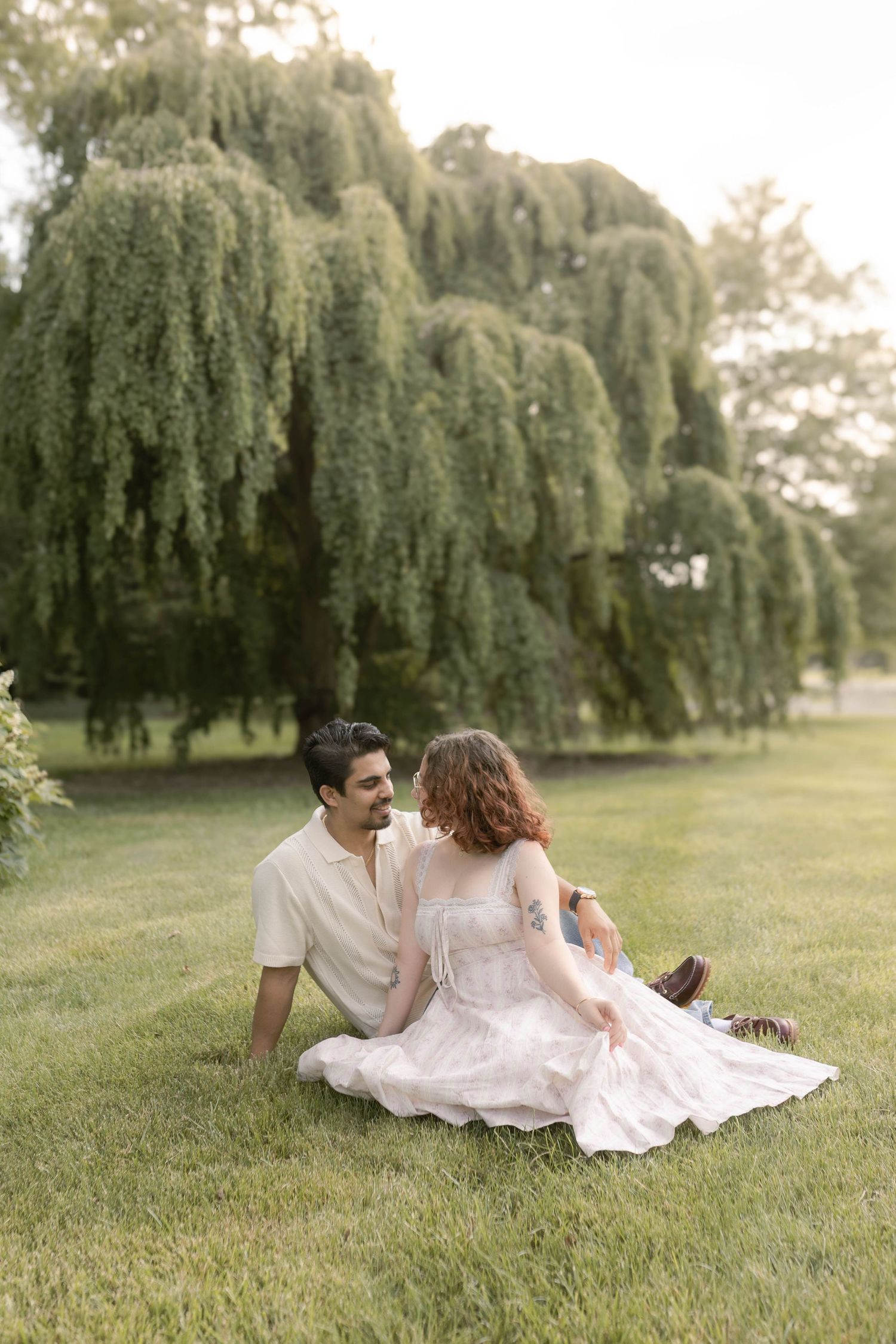 Couple sitting in front of willow trees at park