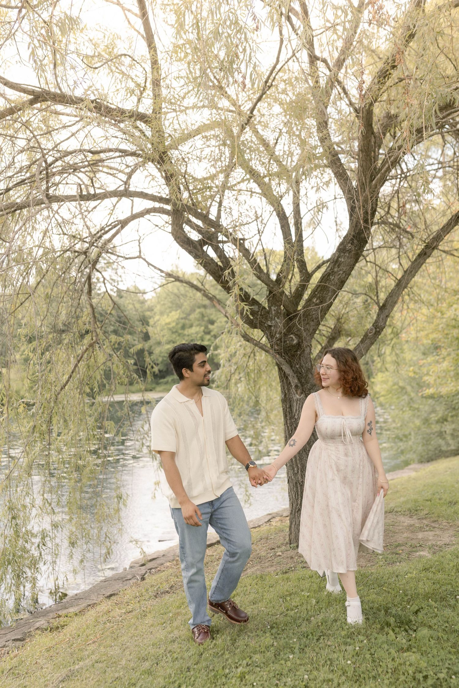 Couple walking together in front of trees and pond at the cemetery