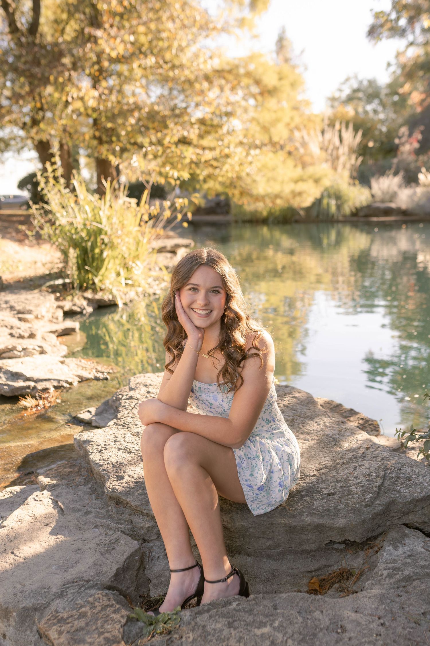 Senior girl sitting on rock in front of pond