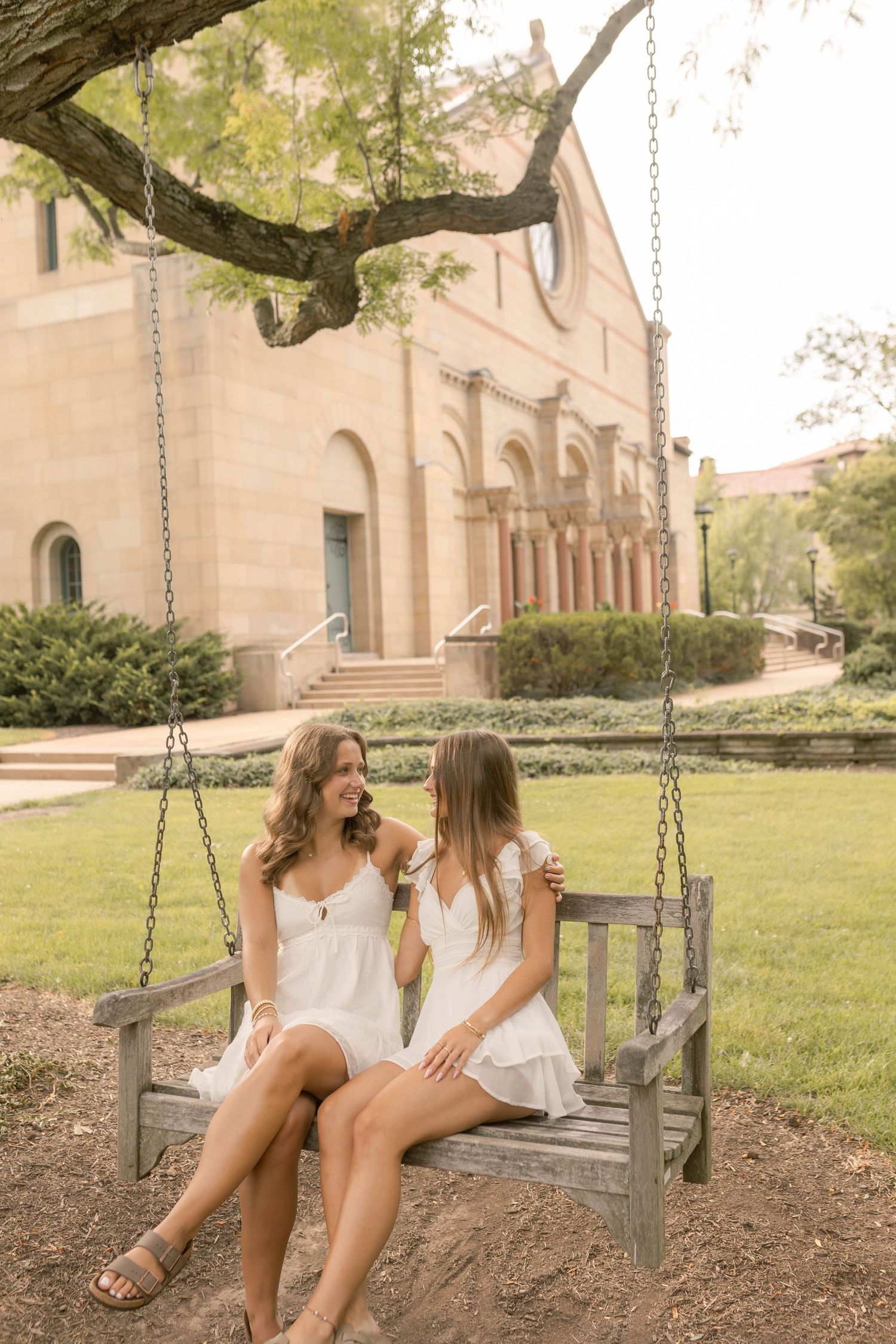 Best friend senior photos outdoors during sunset at park on swing