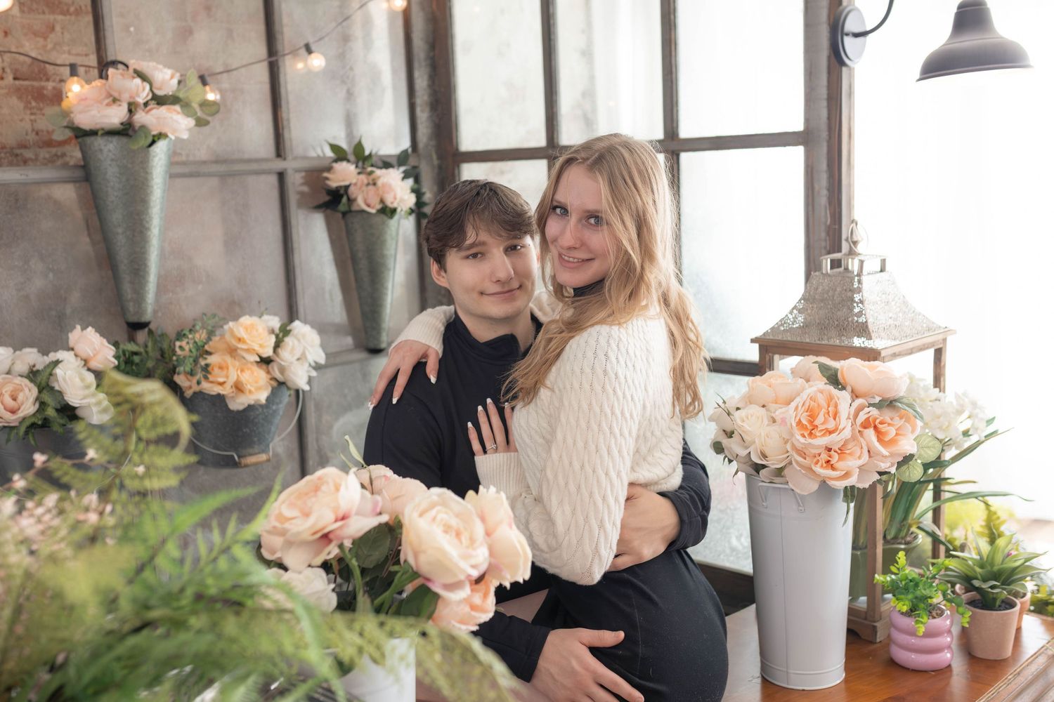 Couple embracing wearing winter clothes in flowery studio
