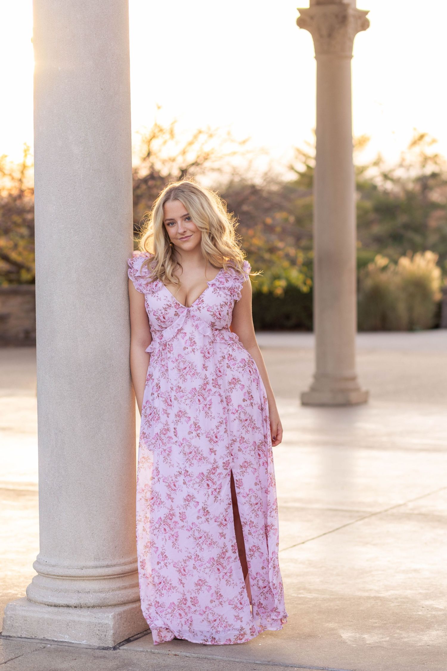 Teen girl leaning on marble column during outdoor senior photo session