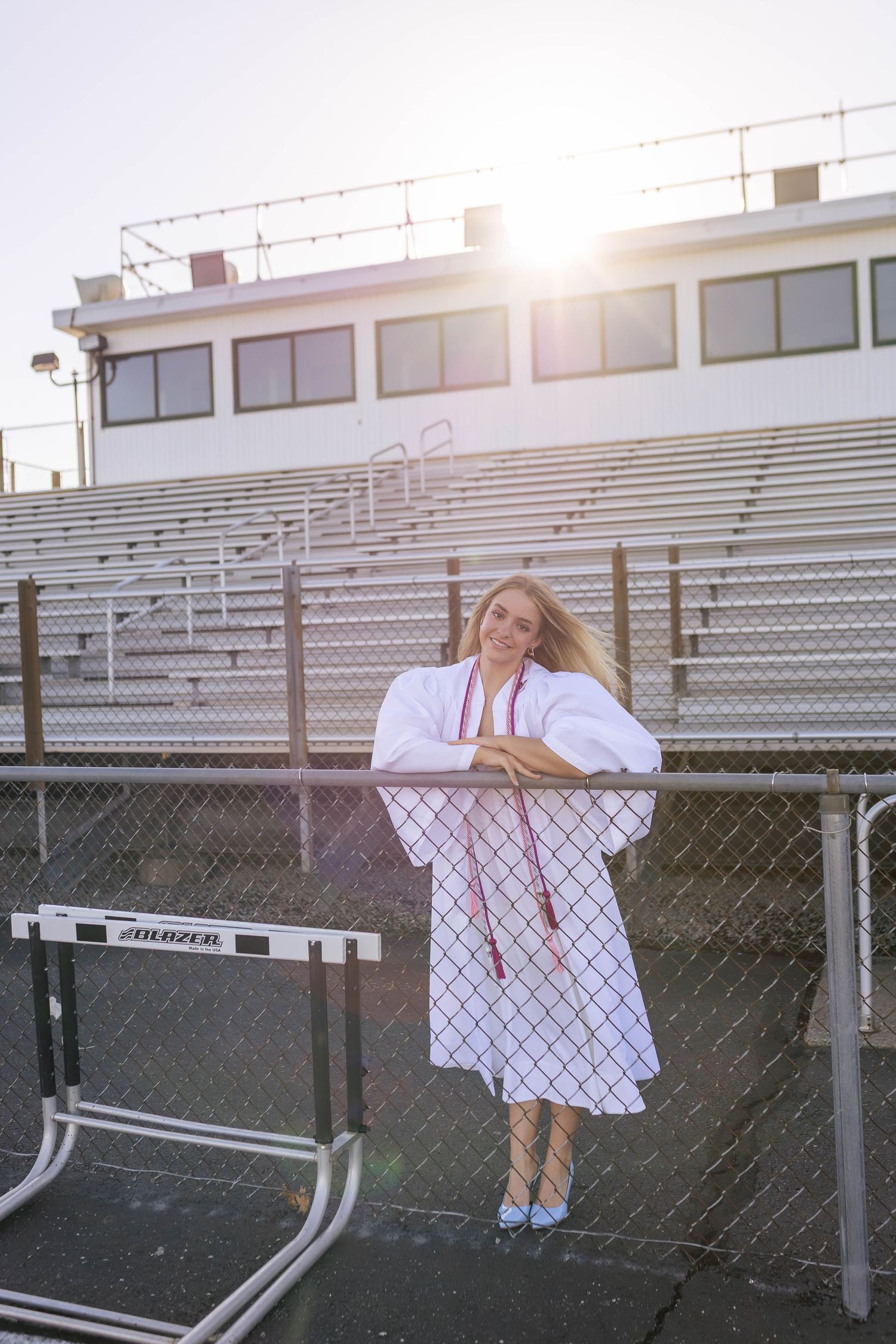 High school graduation photos on track with cap, gown, and diploma