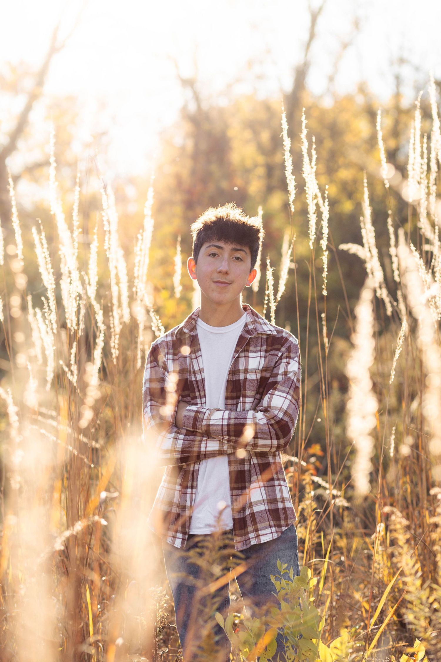 Teen boy posing in open field for senior pictures at golden hour
