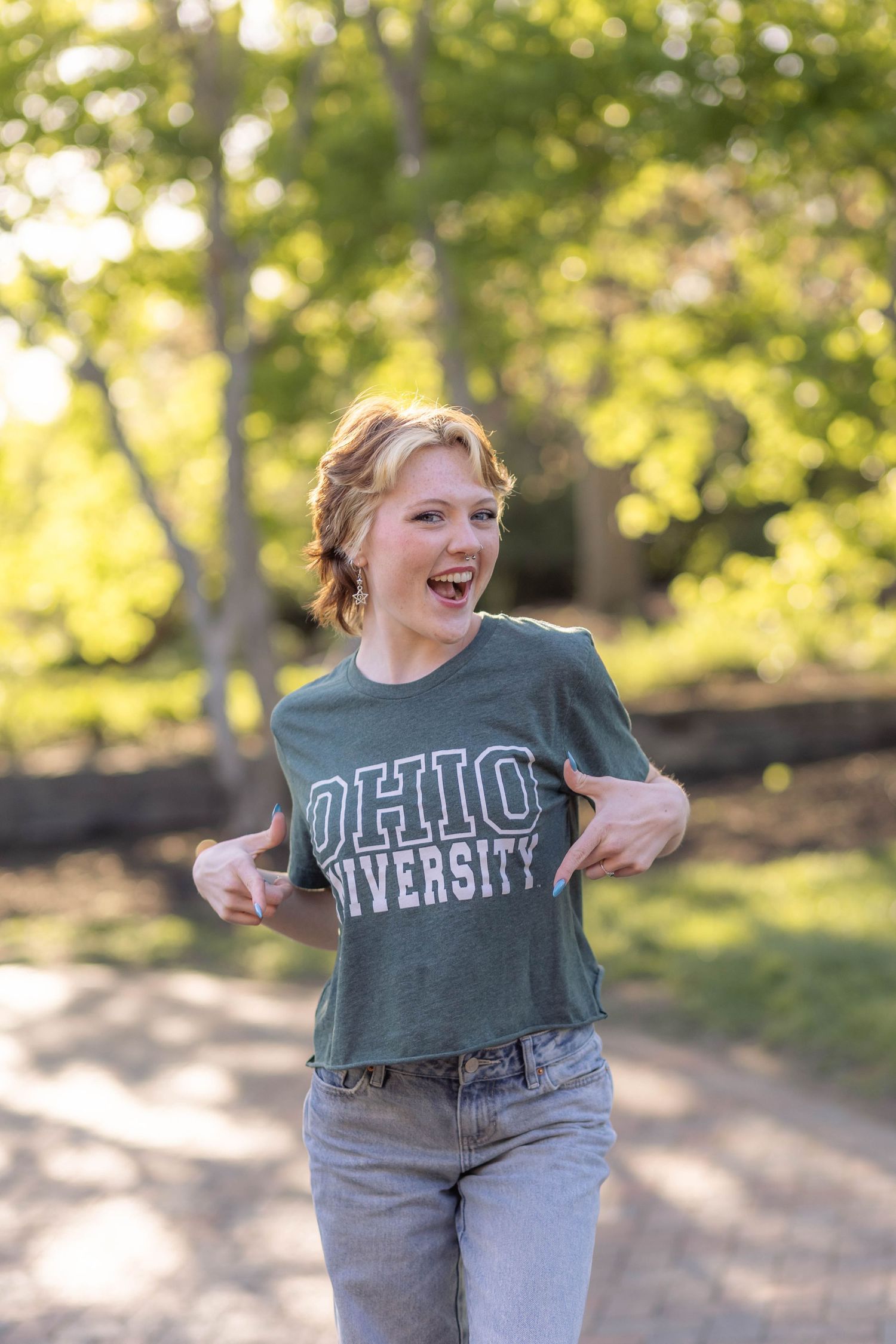 Senior photo of teen girl smiling outside with college t-shirt