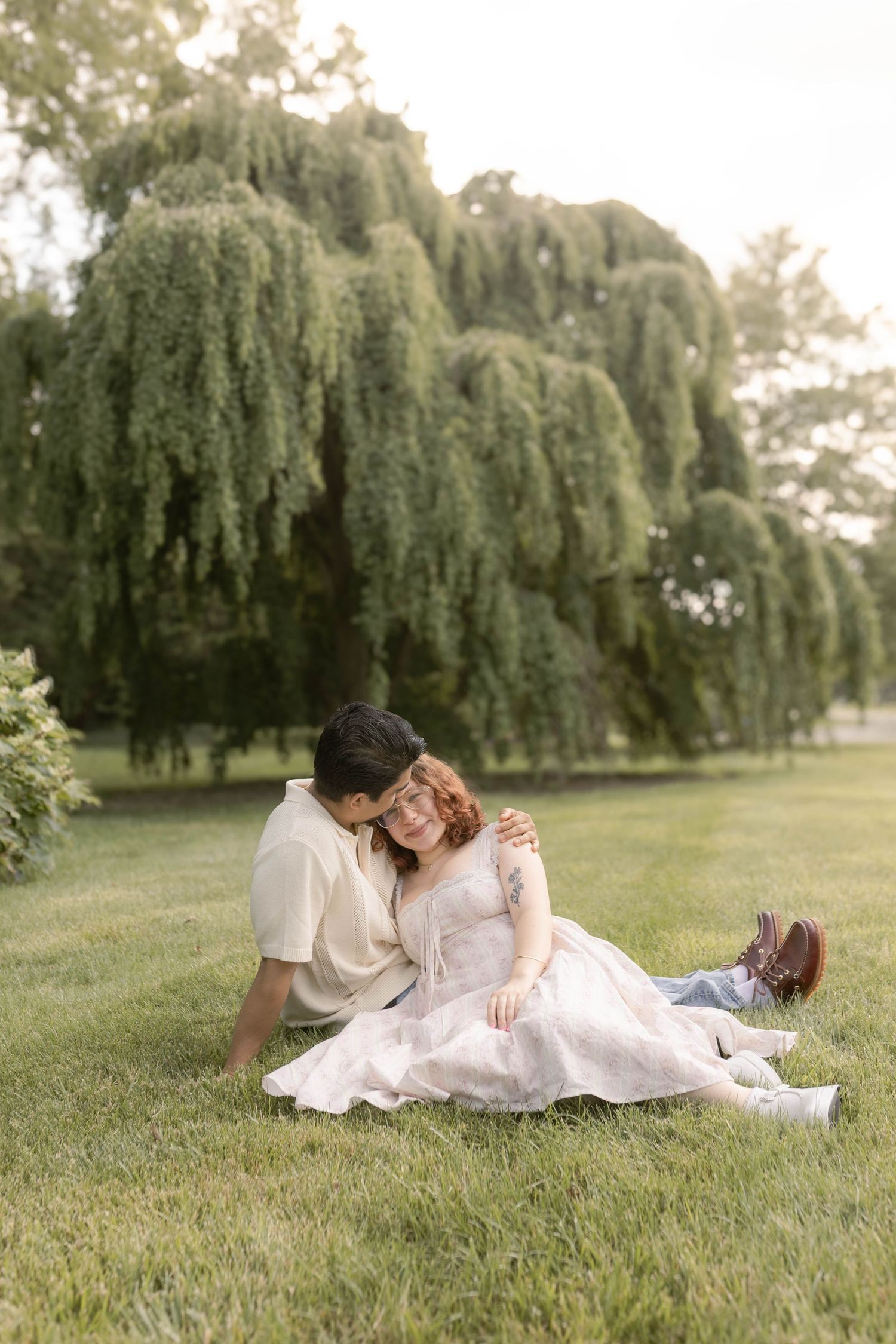 Couple sitting together in front of willow tree at the cemetery