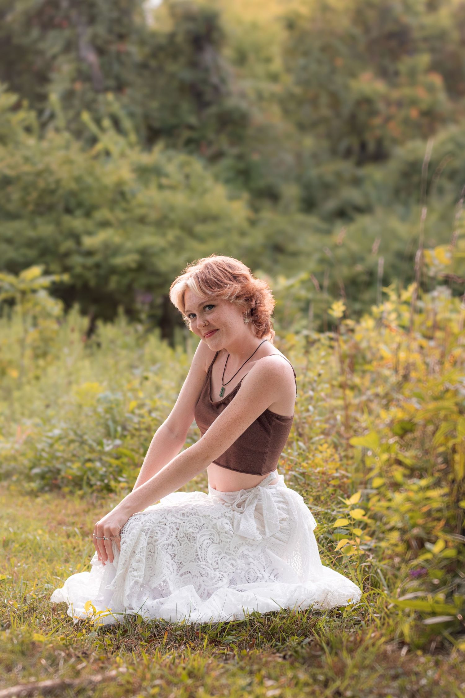 Outdoor senior portrait in green field with soft afternoon lighting