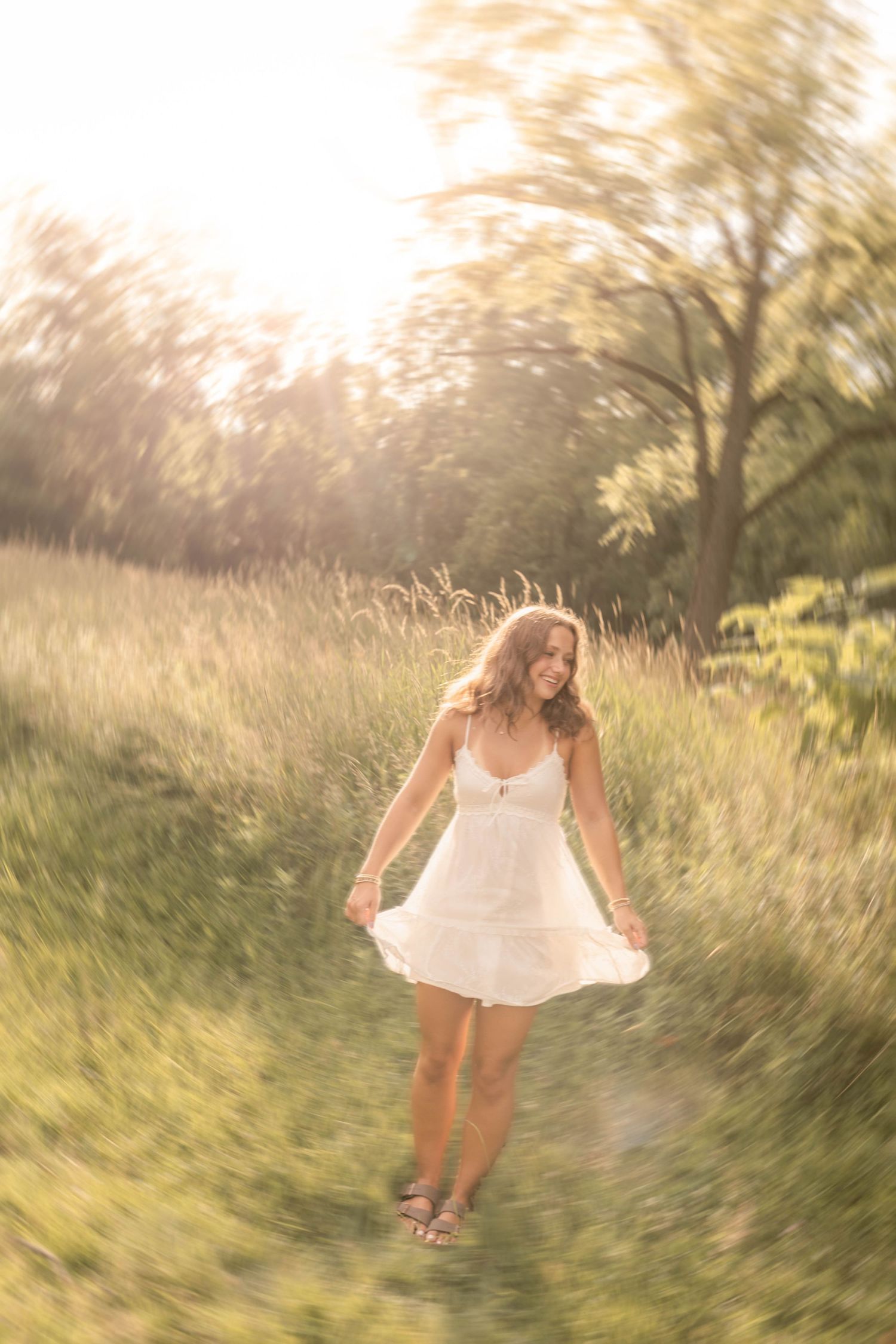 Senior standing in field during golden hour in white dress