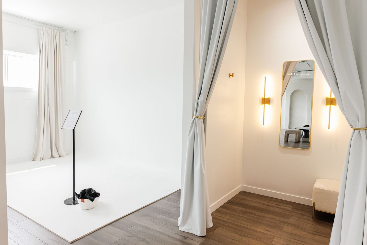A bright, minimalist bedroom interior with white curtains, wall sconces and large windows creating an airy atmosphere.