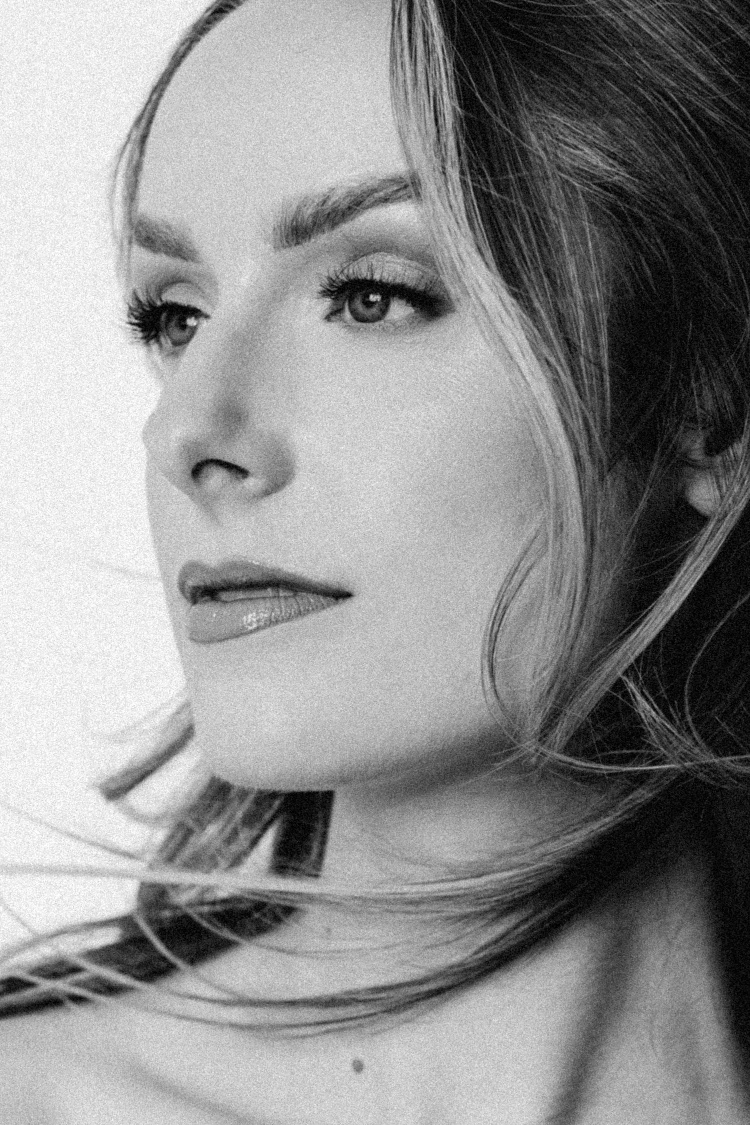 Black and white portrait of a woman with dramatic eye makeup looking upward in an artistic pose.