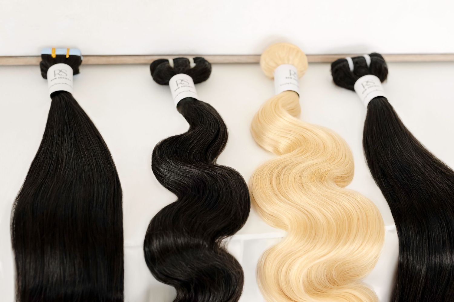 Hair extensions in black and blonde colors showing straight and wavy textures displayed on white background.