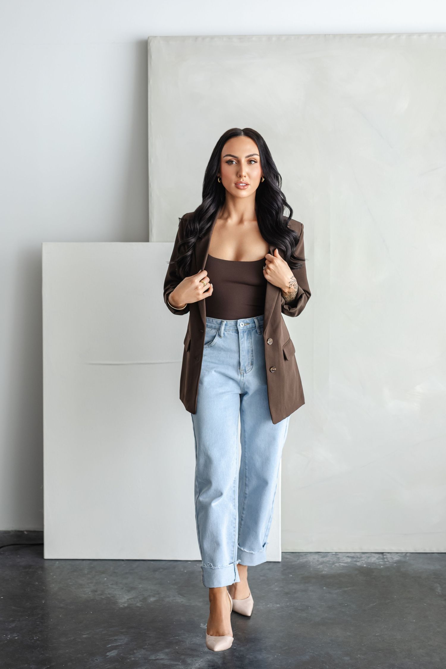 Stylish outfit featuring light wash mom jeans, brown blazer and white heels creates modern business casual look.