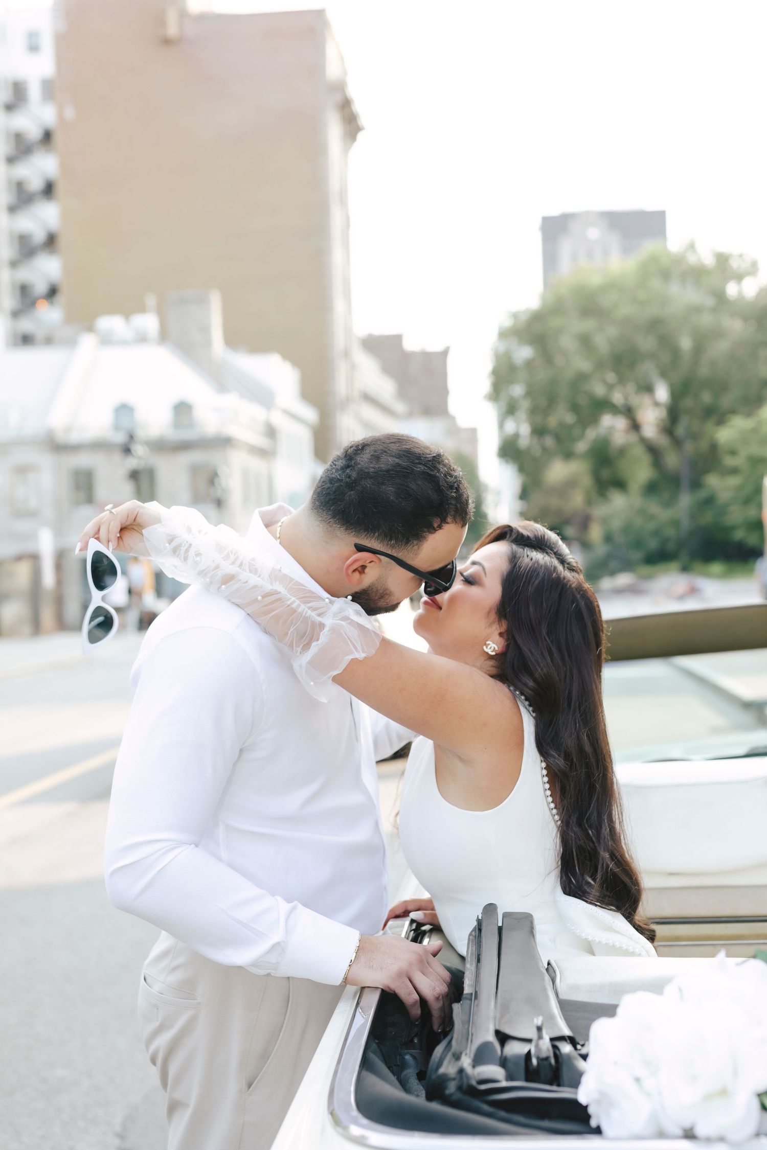 Romantic couple in white clothing share tender kisses in a series of four outdoor photos.