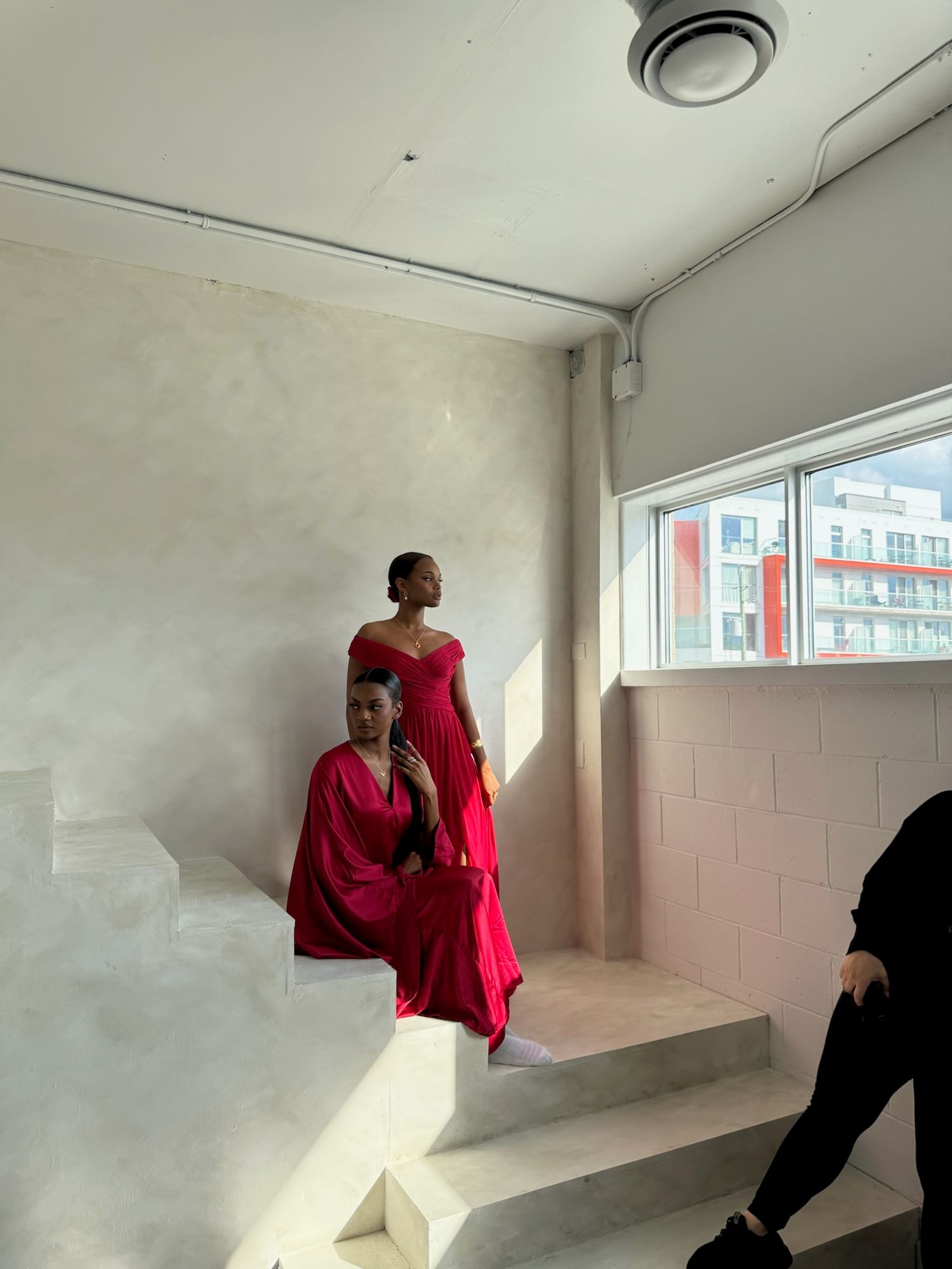 Fashion photoshoot in progress in a bright white studio space with large windows.