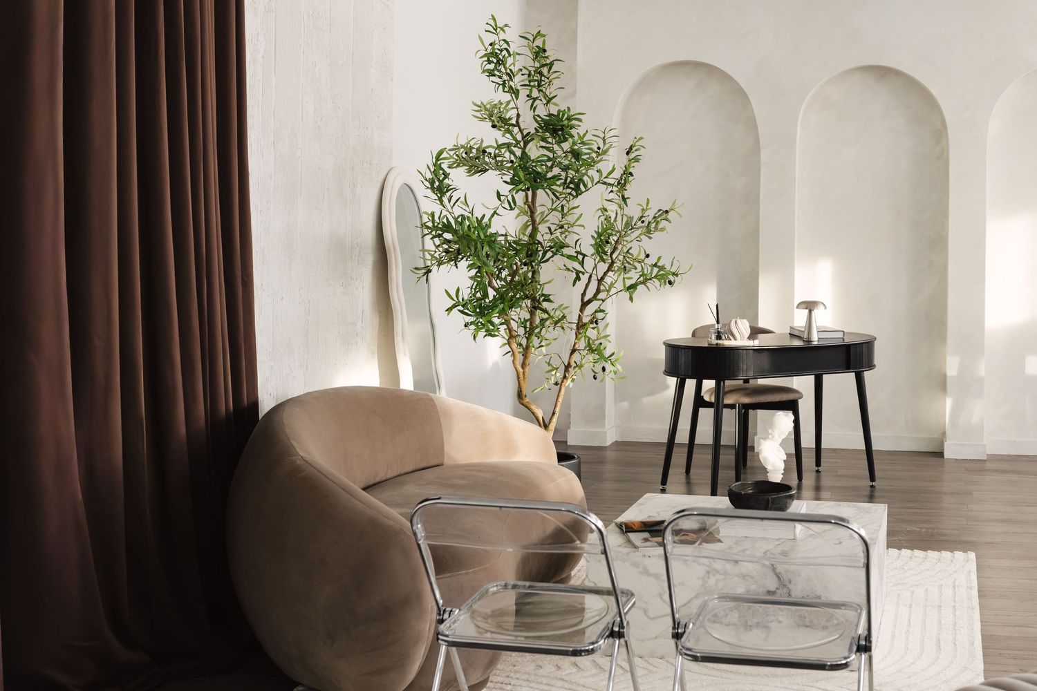 Minimalist white living room interior with beige accent chair, potted plant, and modern design elements.
