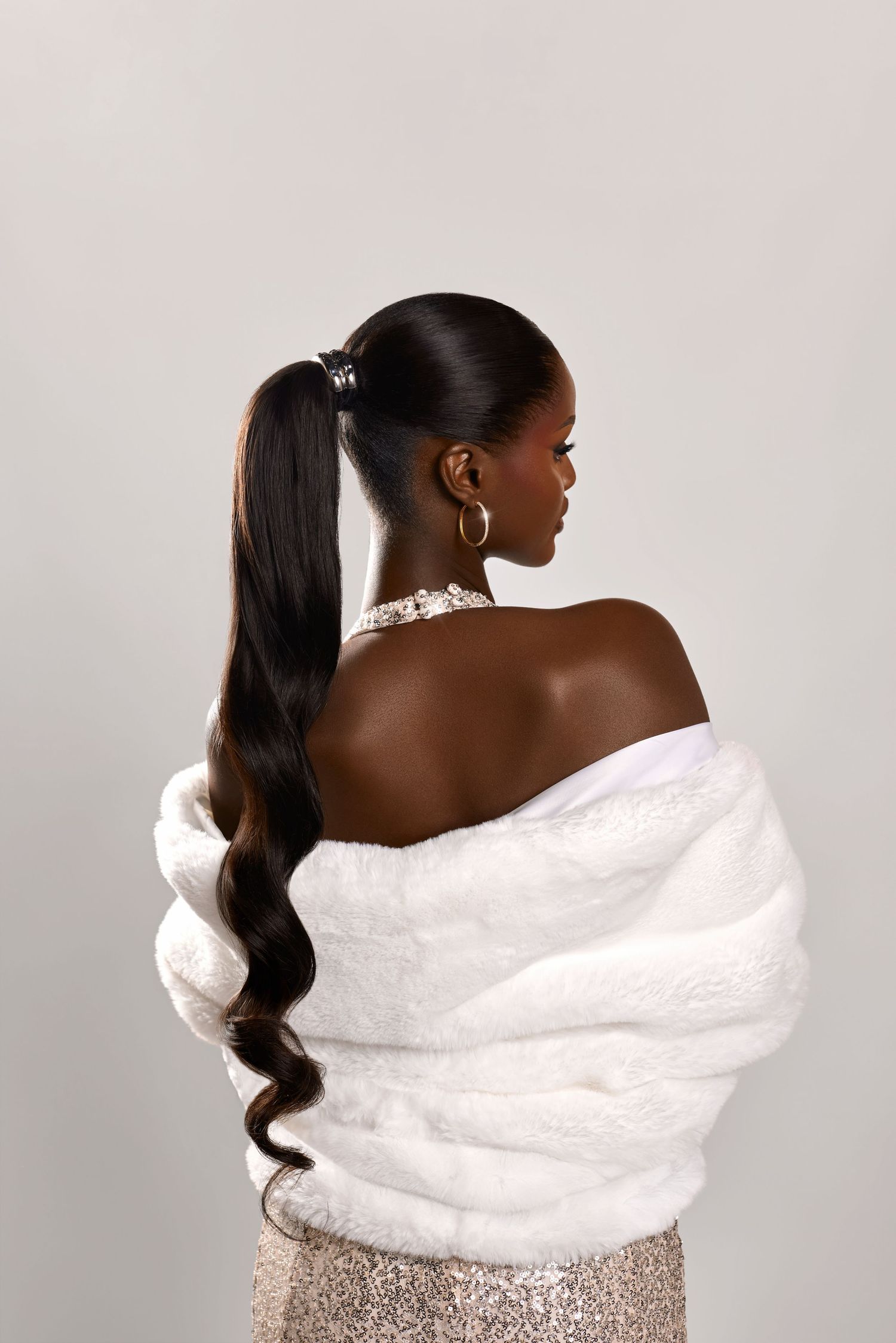 A person wearing a white fur stole and sparkly dress poses elegantly from different angles against a light background.