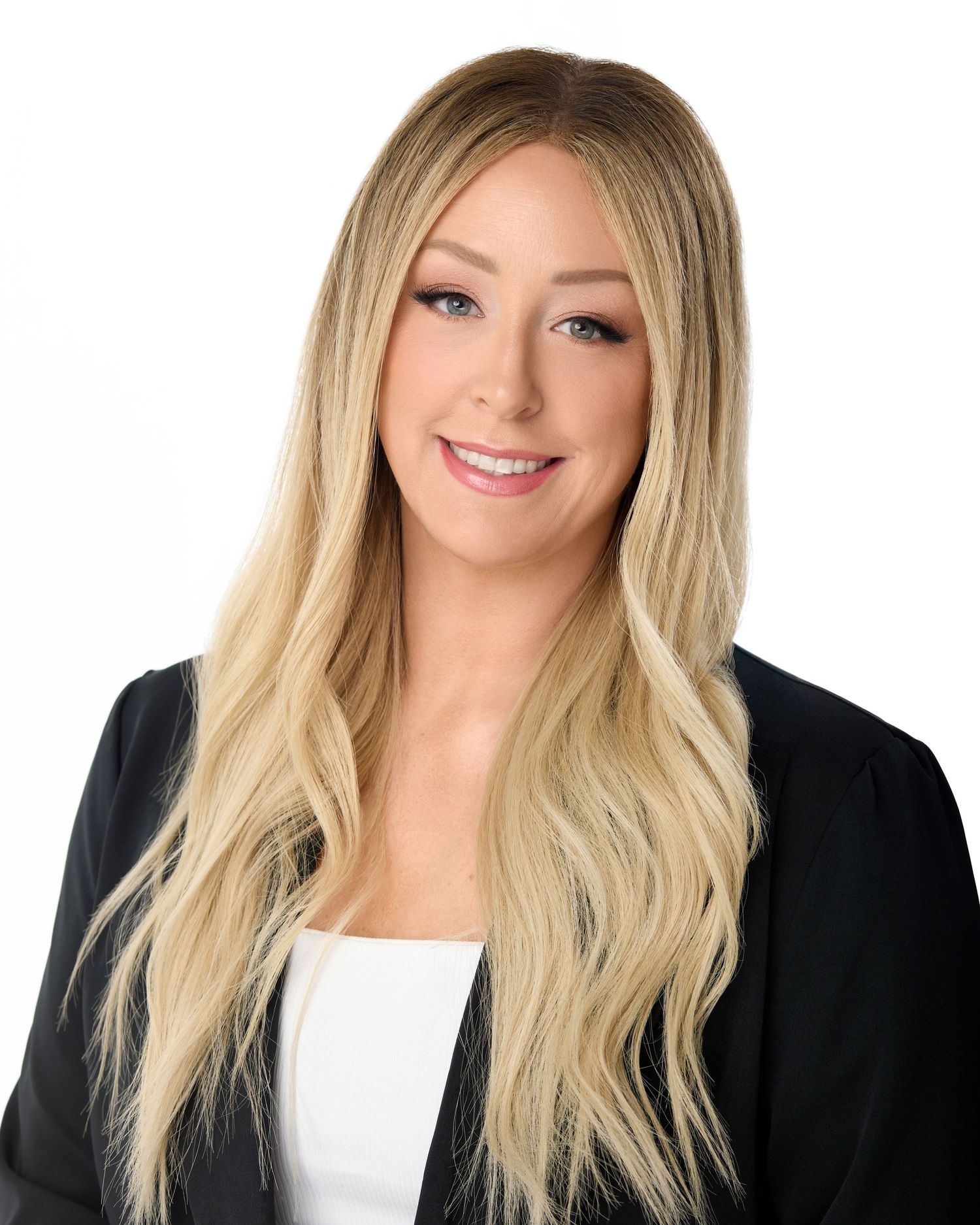 Professional headshot of a smiling blonde woman in a black blazer and white top against a white background.