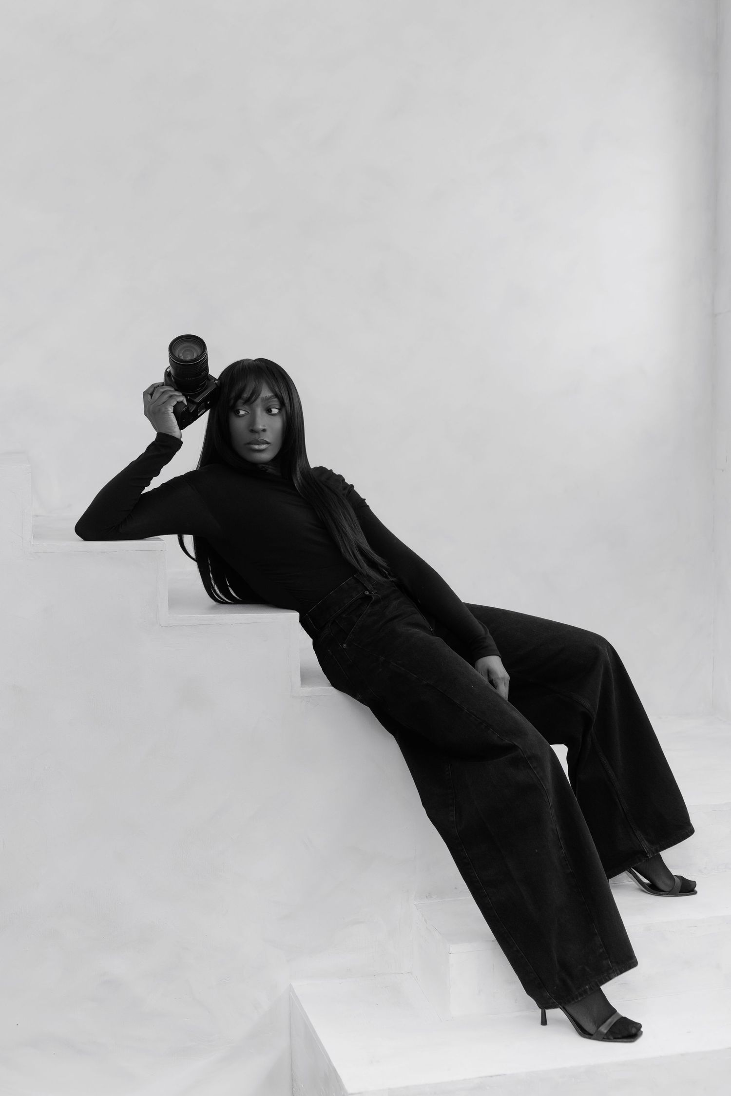 A figure in a flowing black outfit poses dramatically against a white background in a series of artistic movements.