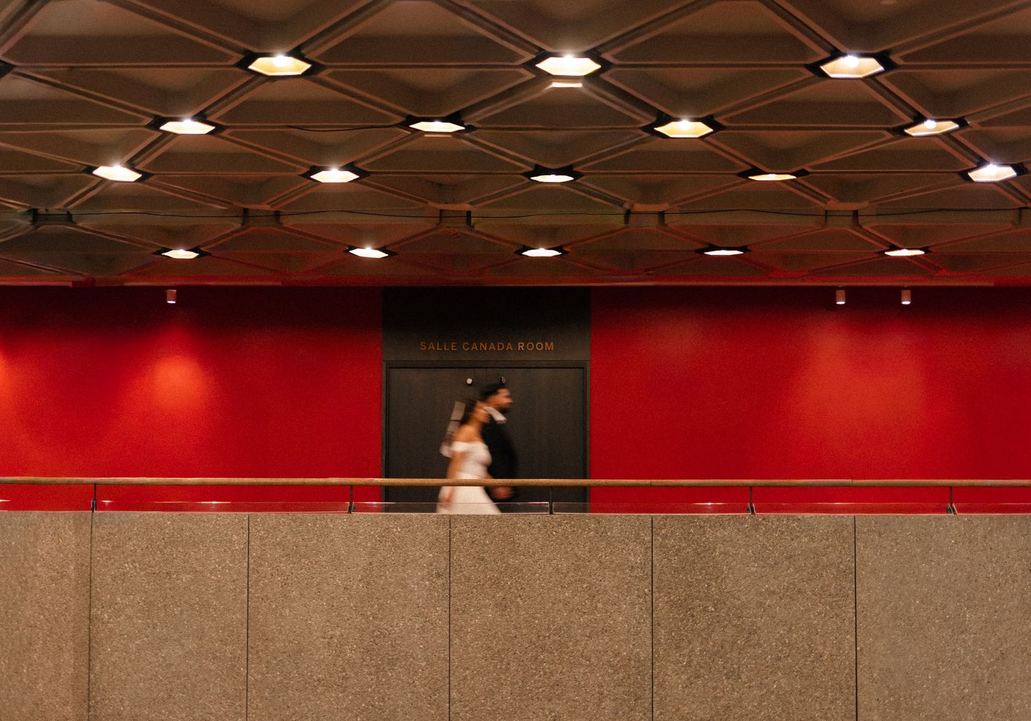 A long horizontal panoramic view of a modern indoor space with recessed lighting and red accent walls.