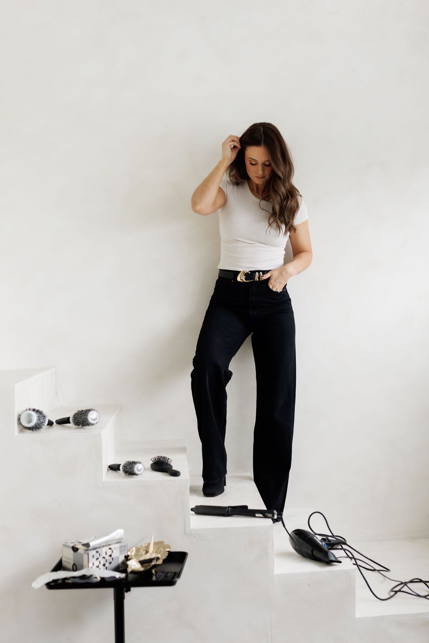 A person poses in various positions while wearing a white top and black pants against a minimalist white background.
