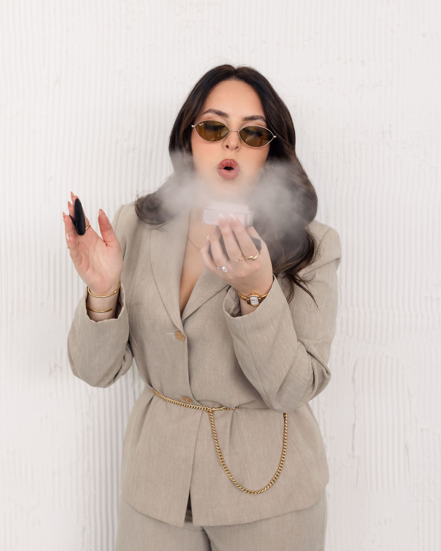 A figure in a beige blazer and gold chain strikes four dynamic poses while surrounded by smoke effects.