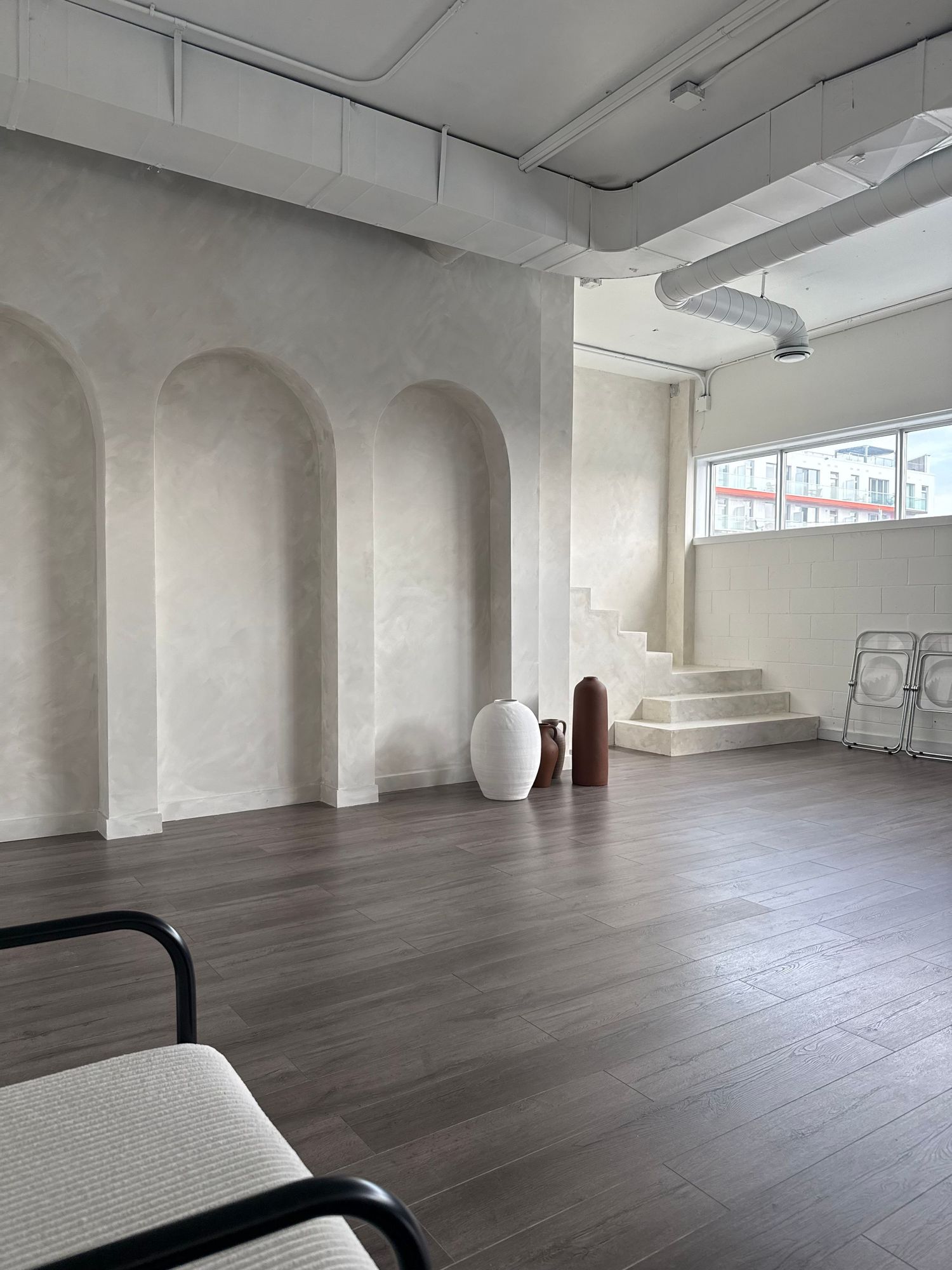 Large open studio space with arched columns and grey hardwood flooring.