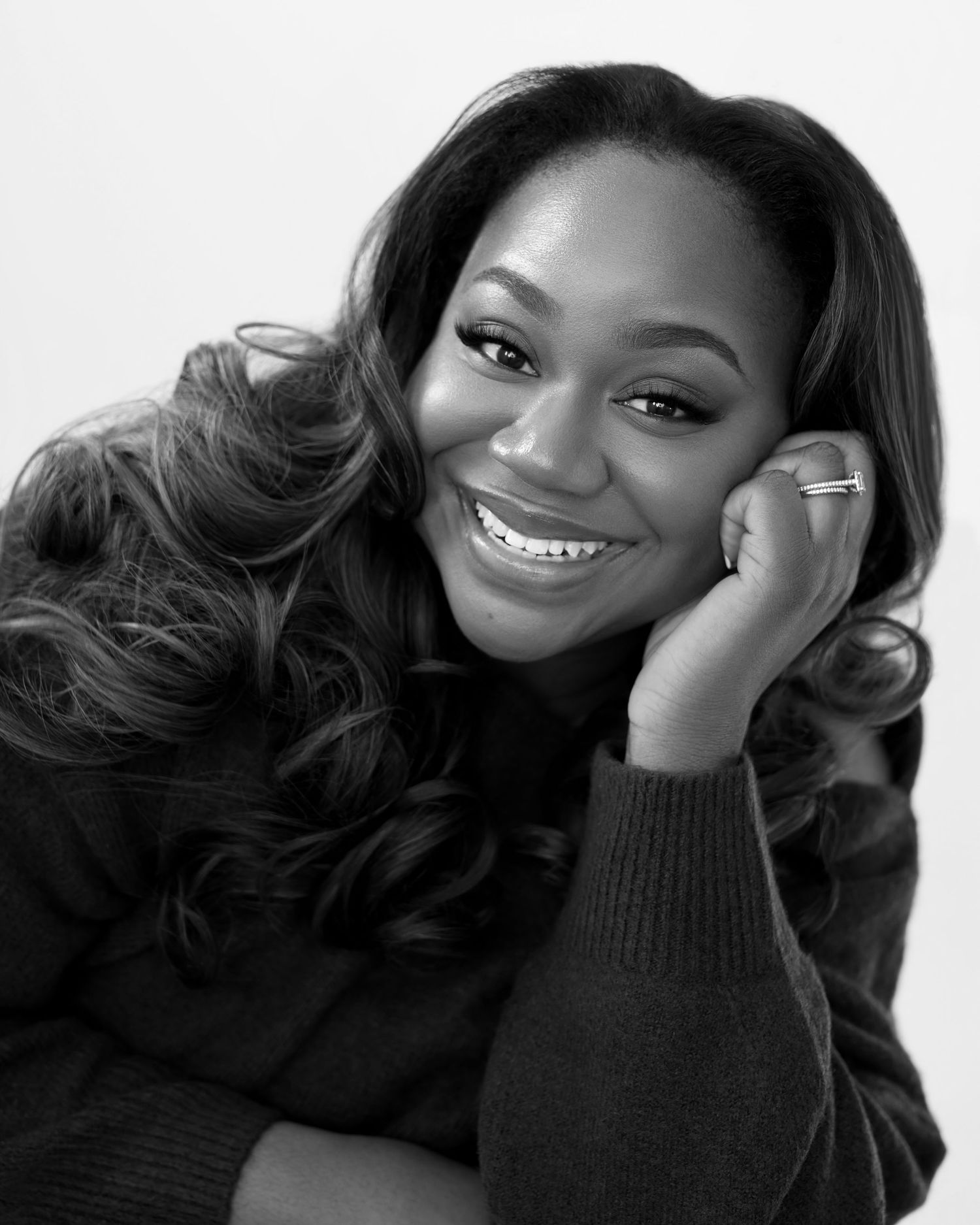 A series of black and white portraits showing someone smiling and posing in a black sweater.