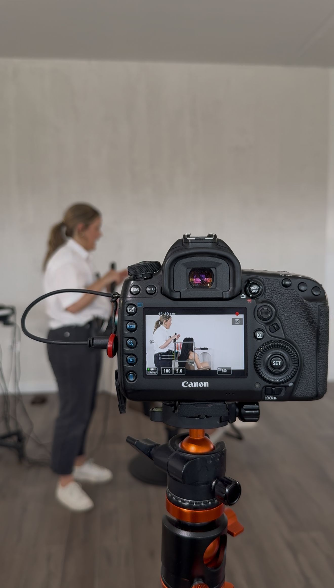 Canon DSLR camera on tripod displays live view screen during indoor video shoot setup.