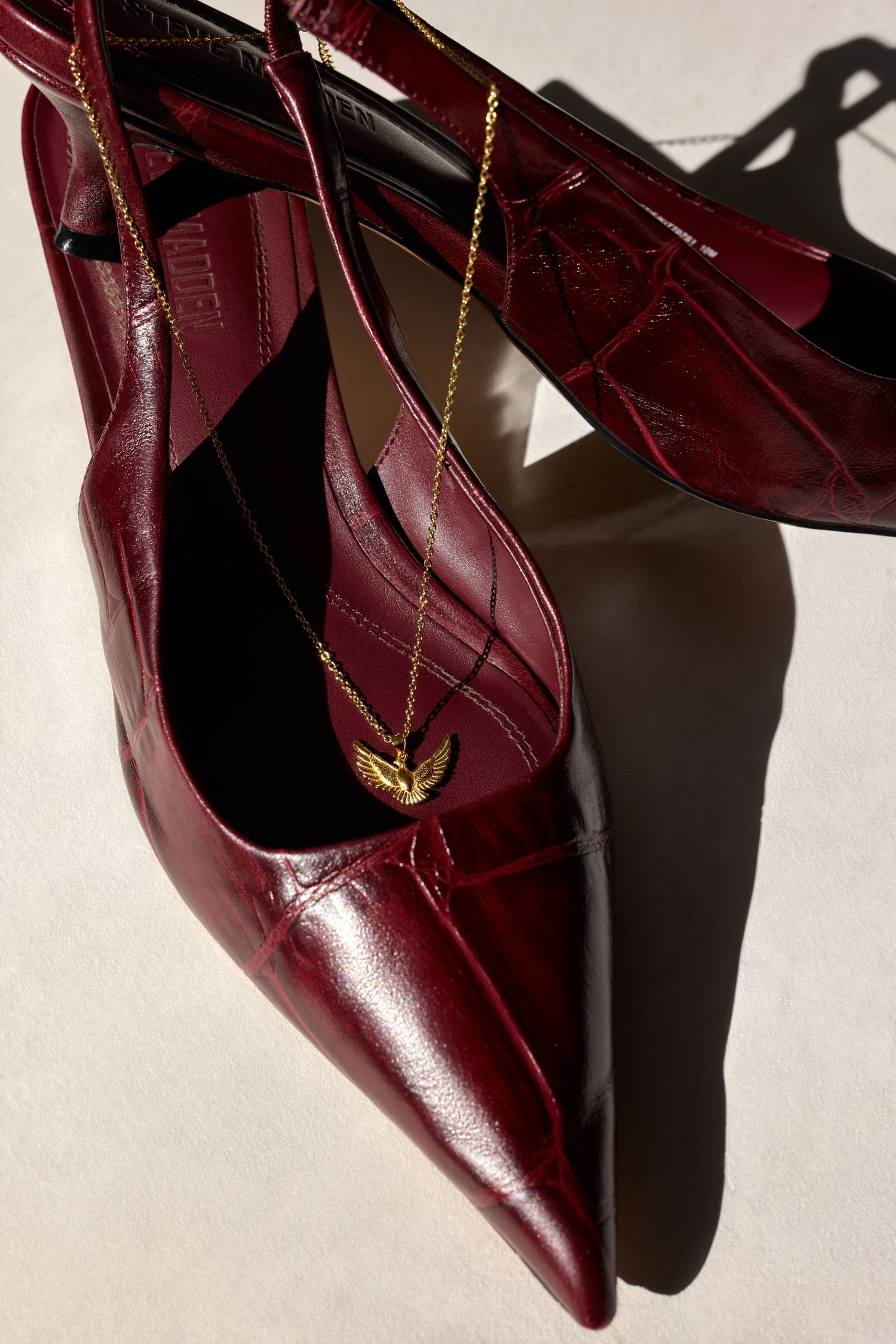 Burgundy leather pointed-toe flats with gold chain detail shown from multiple angles against white background.
