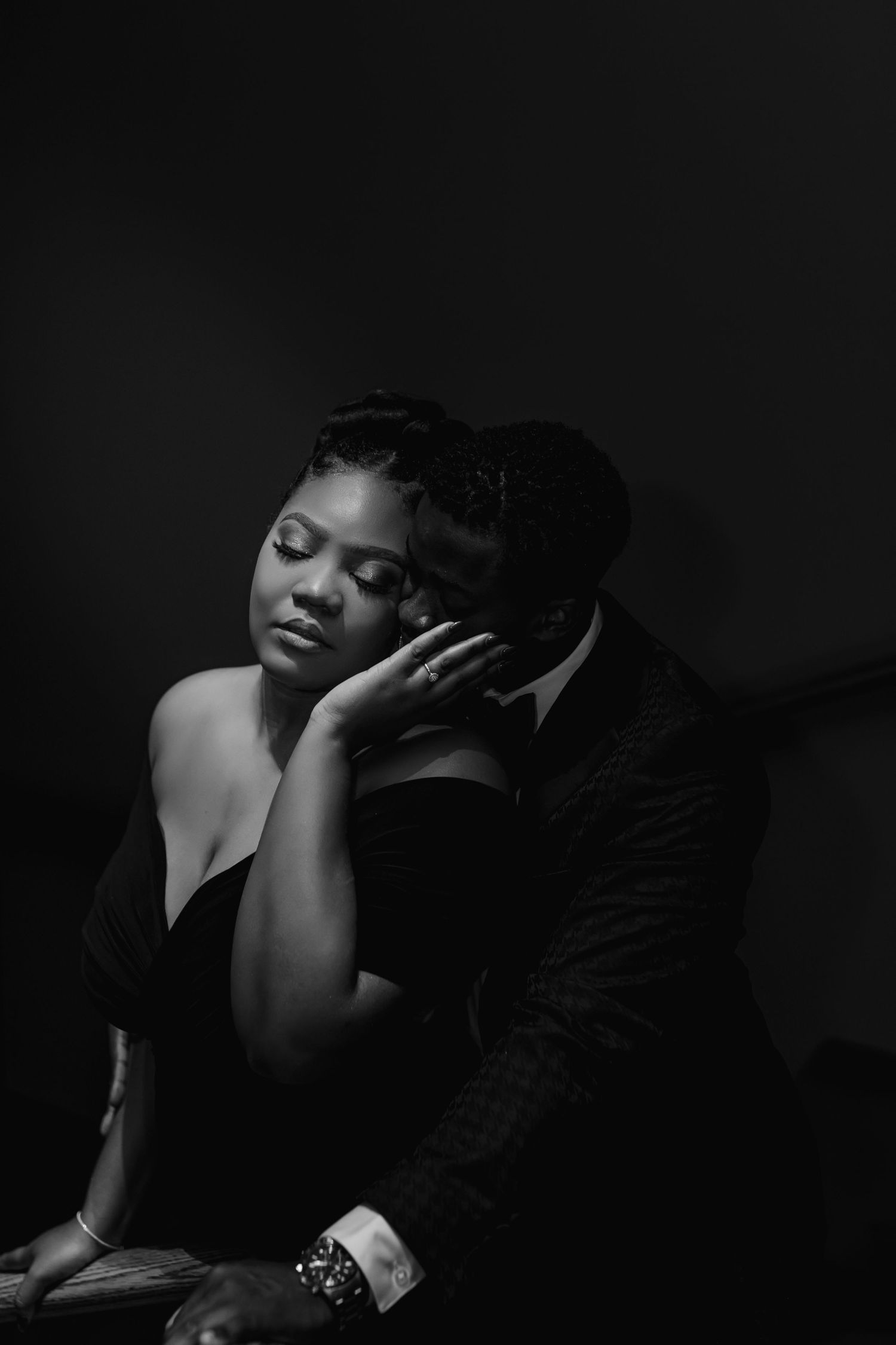 Dramatic black and white portrait series showing intimate poses in dark moody lighting against black background.