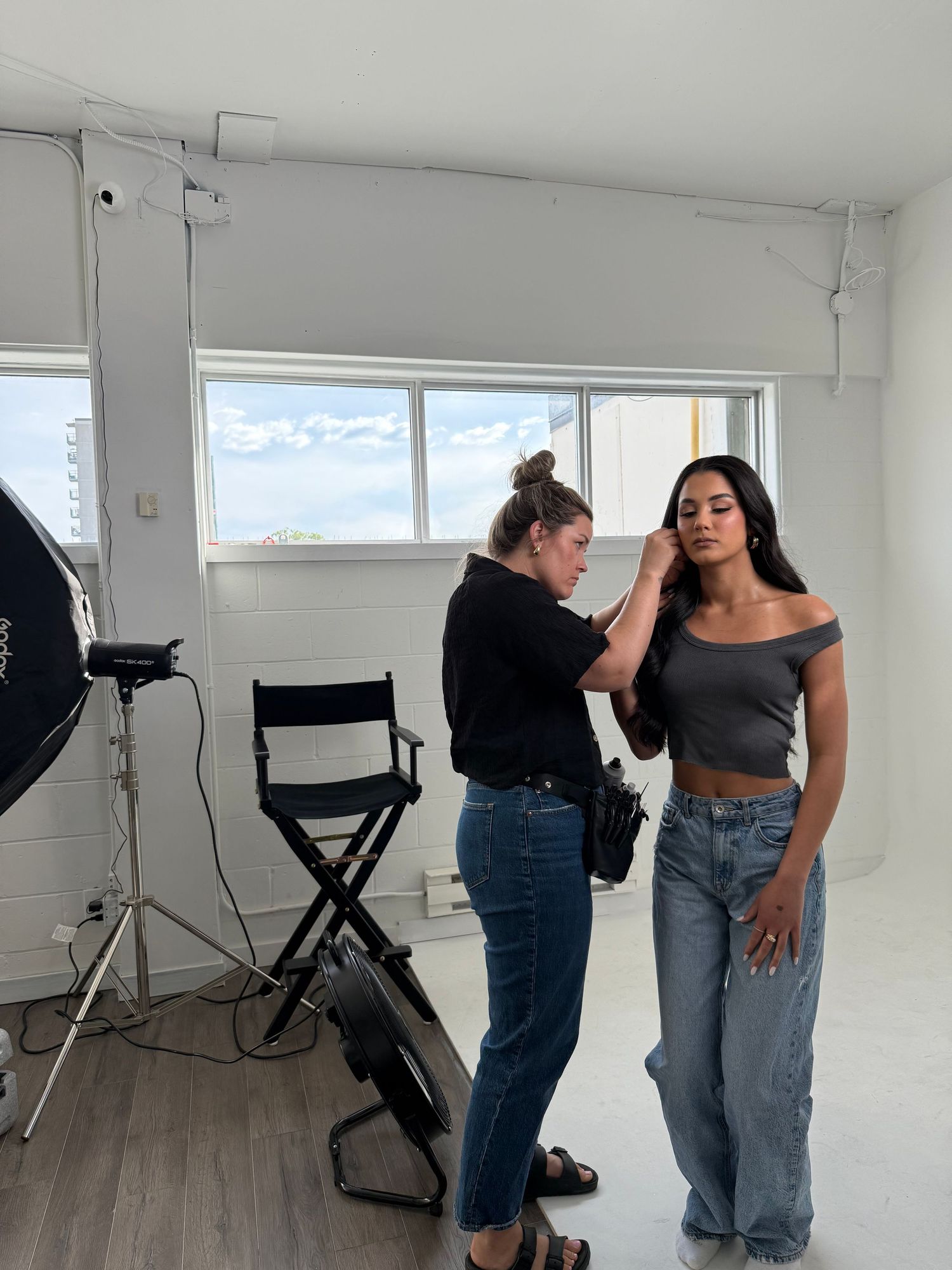 Behind the scenes of professional photo shoot with lighting equipment and crew in studio.
