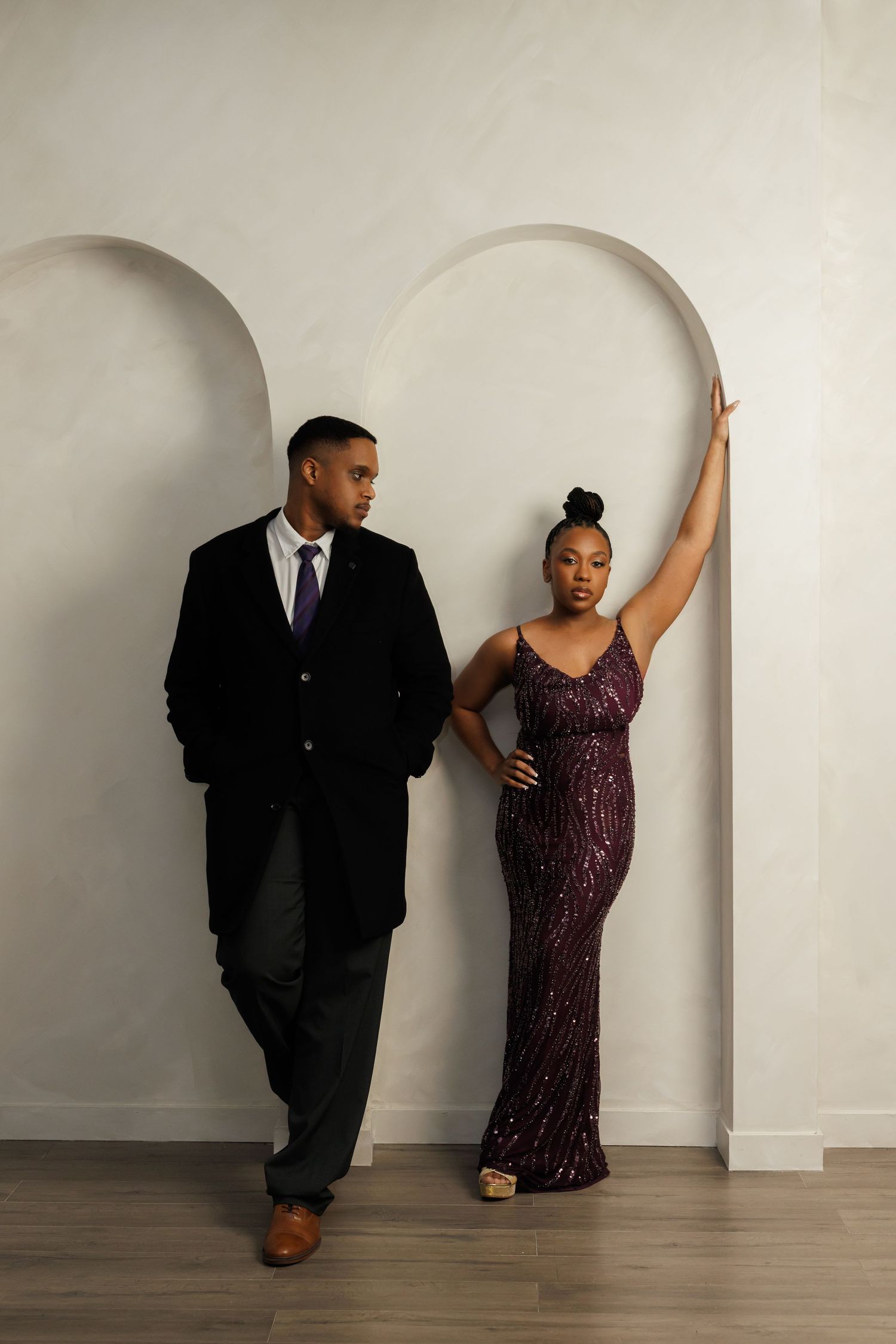 A couple in formal attire poses playfully against a white wall in a series of progressive dance-inspired photos.