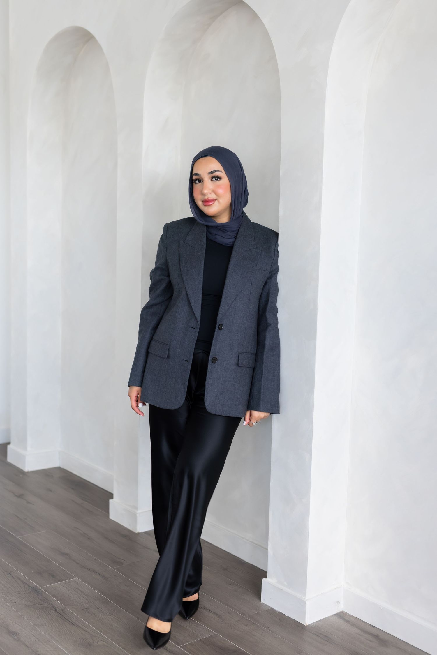 Four views of a person wearing a gray blazer, black hijab, and dark pants in a professional studio setting.