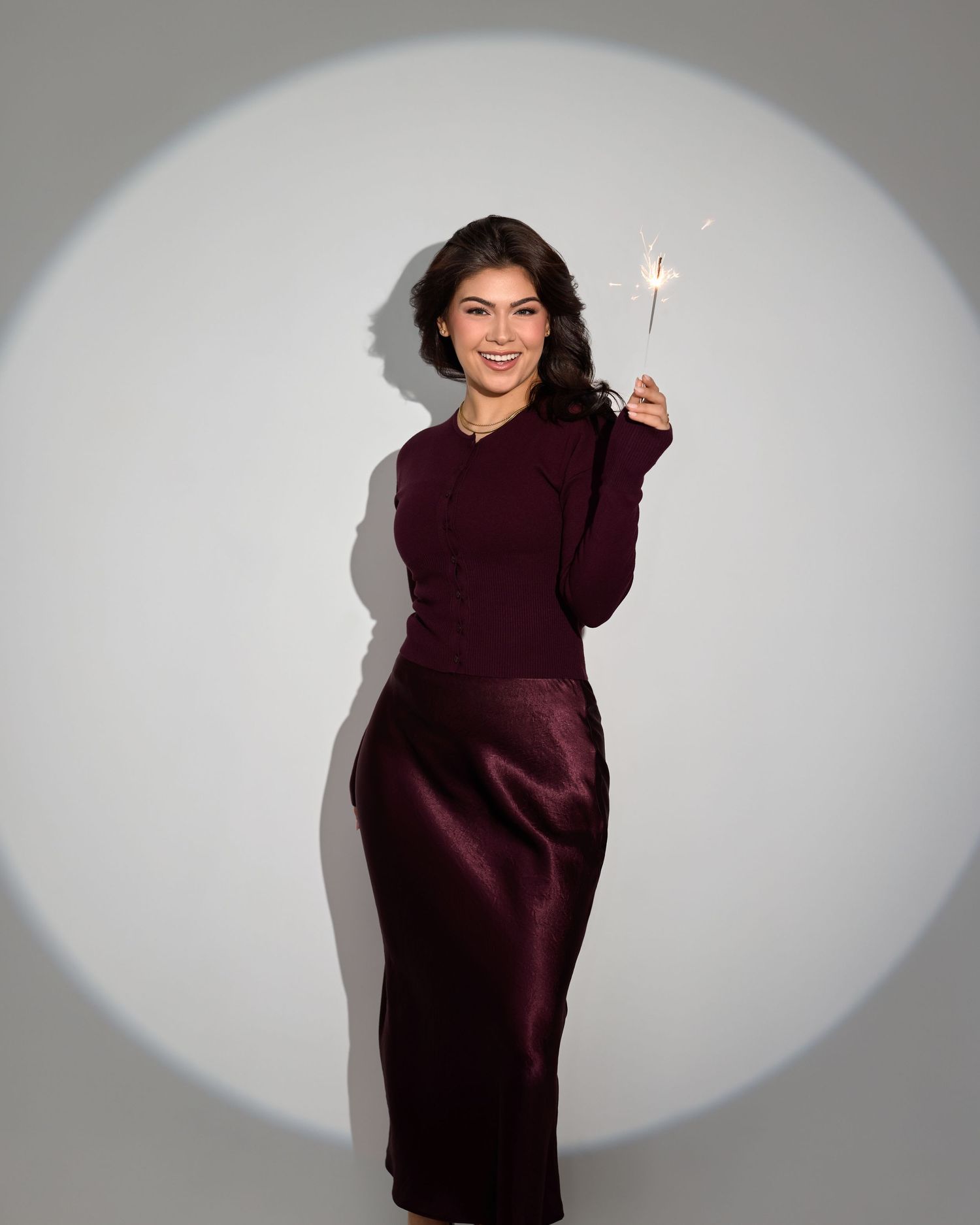 Sequence of someone in burgundy sweater dancing and spinning against a grey studio backdrop.