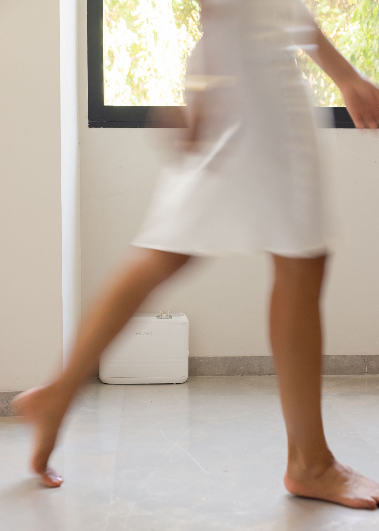 Barefoot woman in white dress walking past window on marble floor, motion blur effect.
