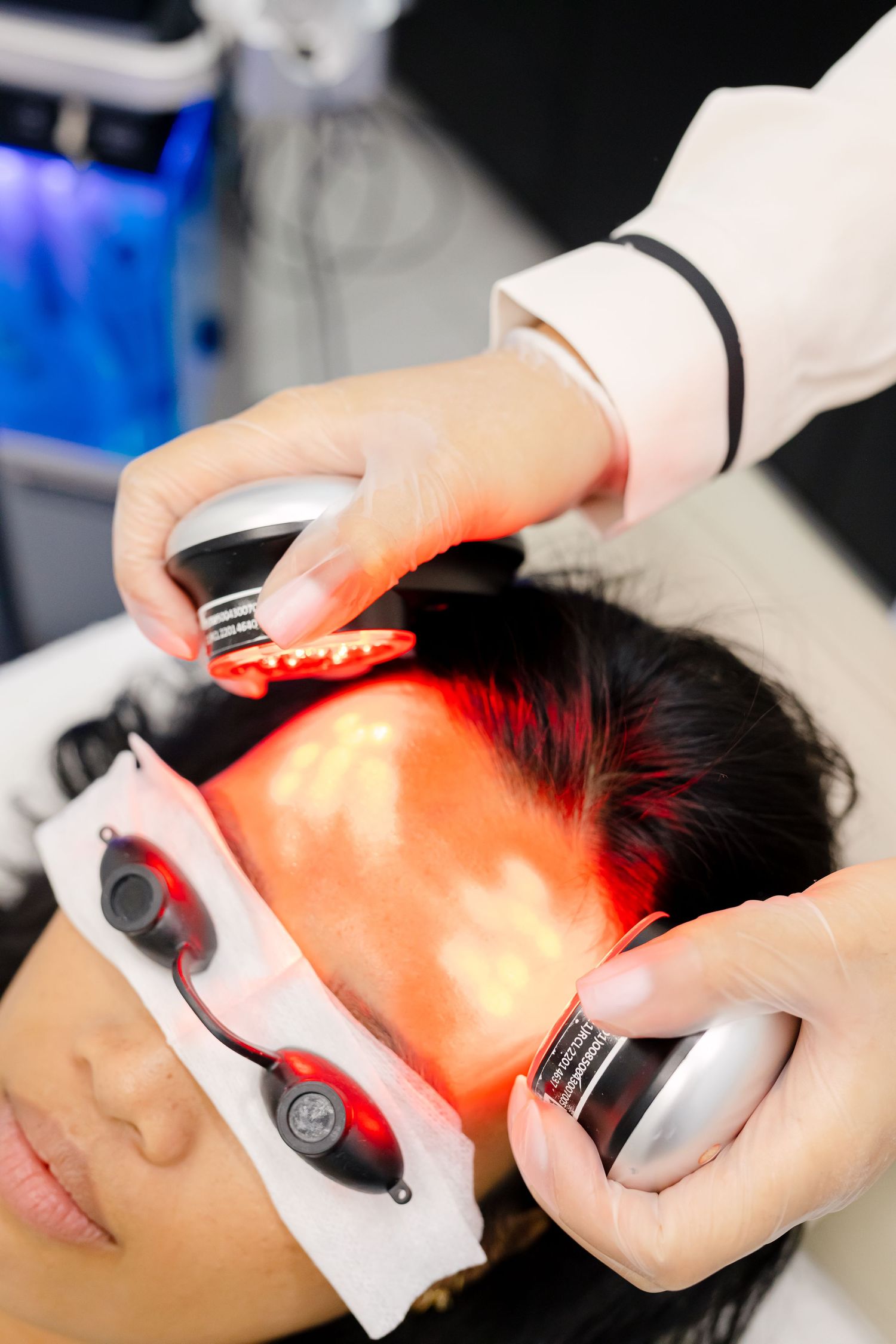Patient receiving red light therapy treatment at a medical spa with protective goggles and professional equipment.