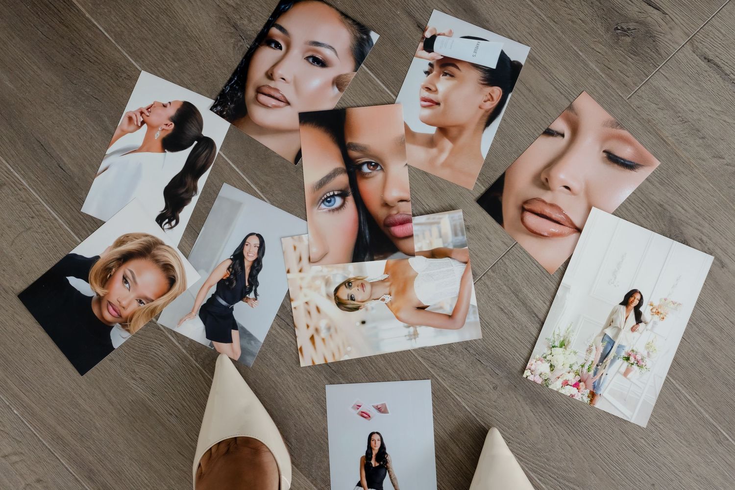 Scattered collection of portrait photos on a light gray wooden surface showing hands arranging printed photographs.