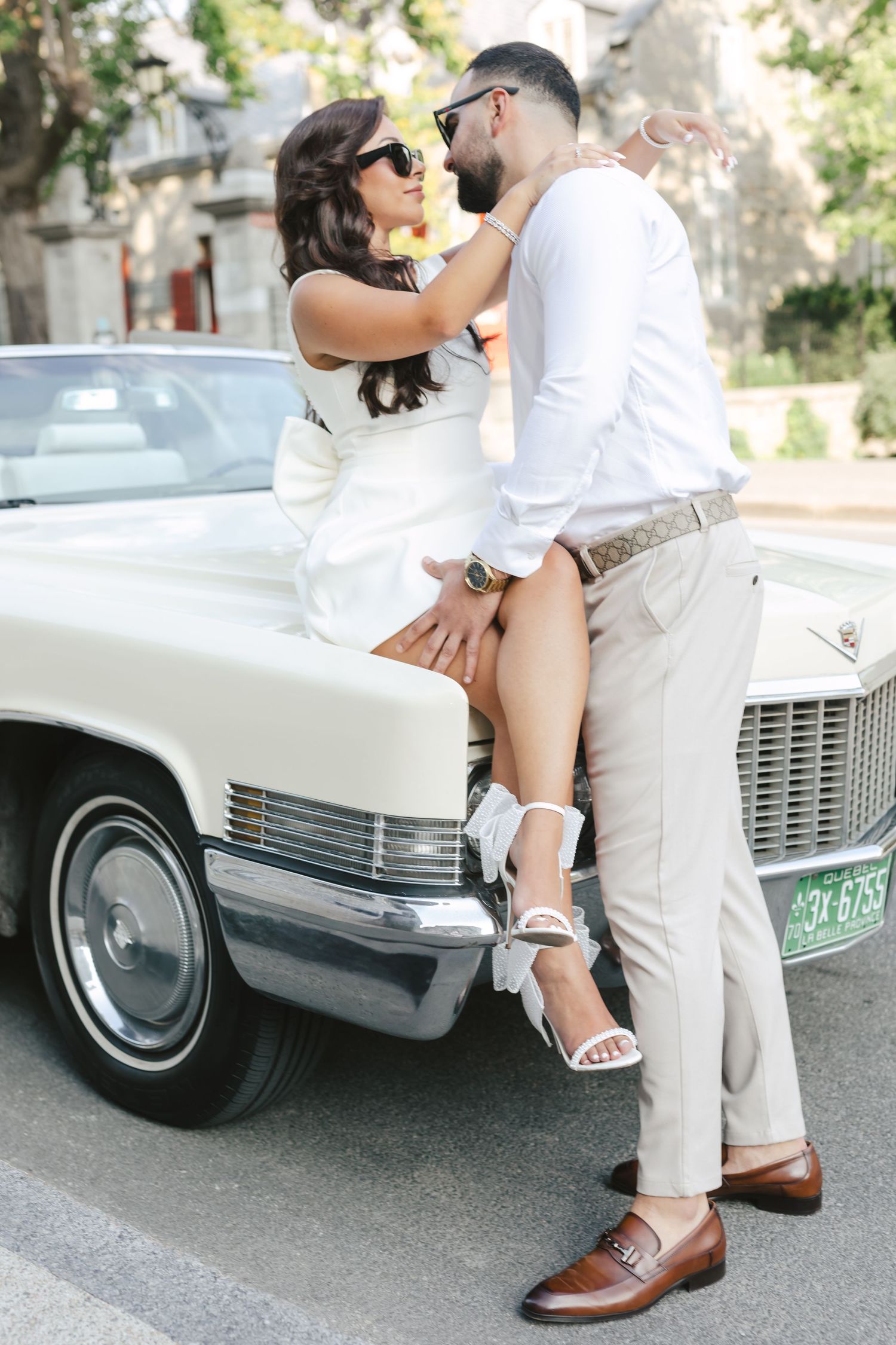 Romantic couple poses by vintage white car in series of intimate shots showing legs and casual summer attire.