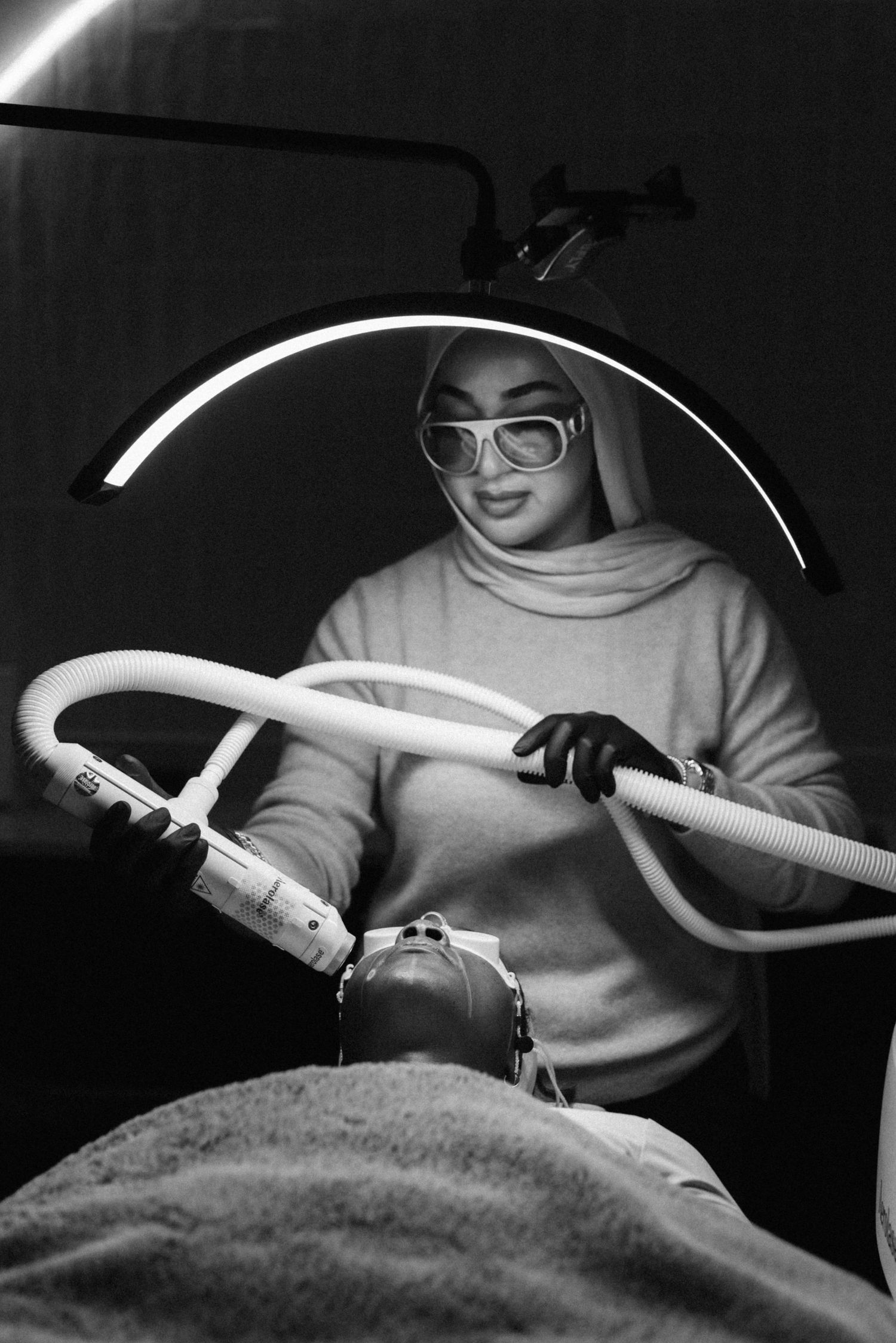 Medical technician operating a CPAP machine in a dark room with white tubing visible against black background.