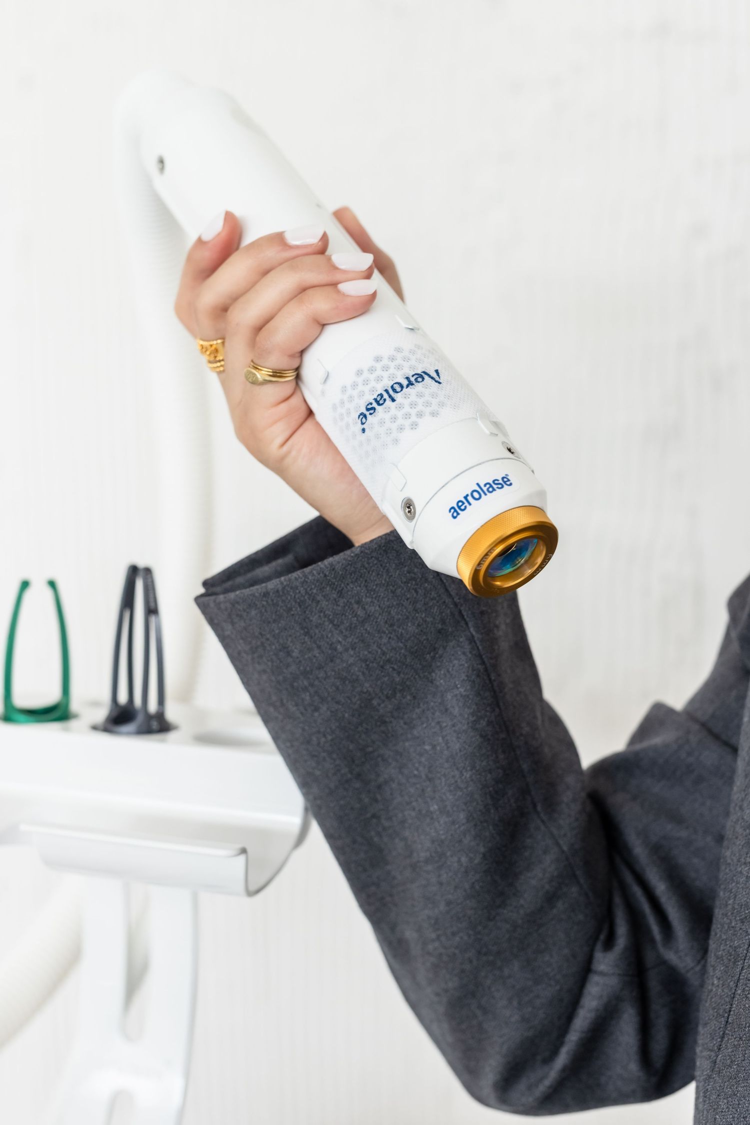 A hand holding an Aerolase laser device in a medical or aesthetic clinic setting.
