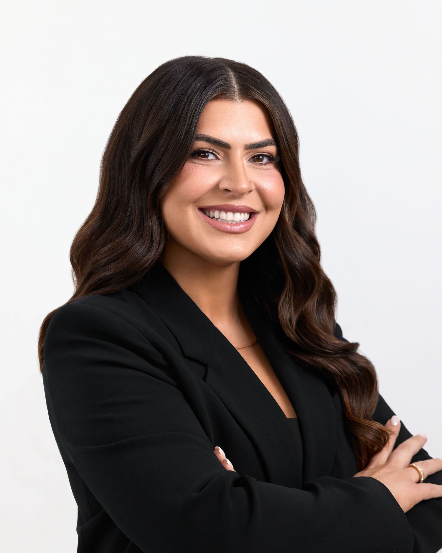 Professional headshot of a person in a black blazer smiling warmly against a light background.