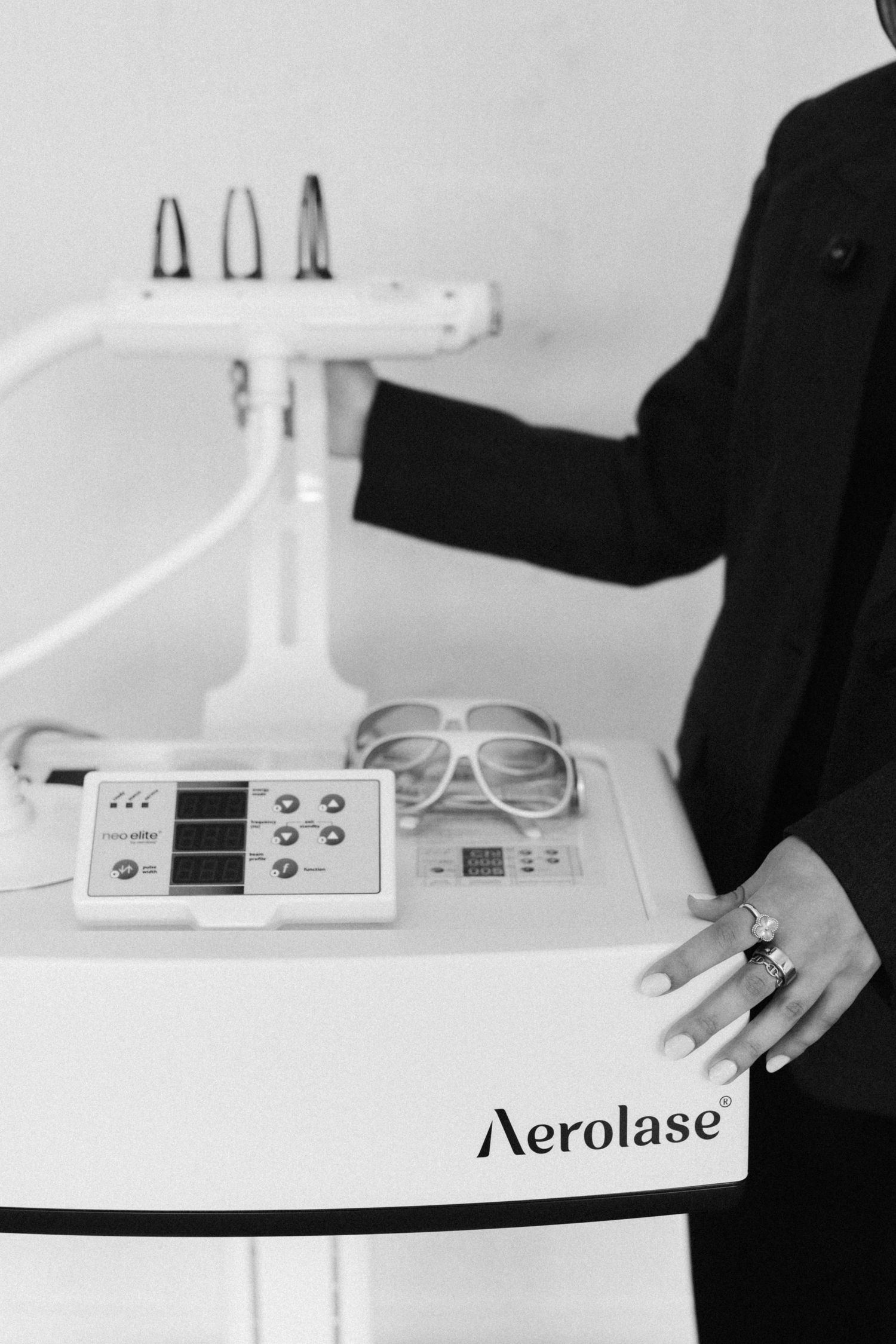 Close-up view of a professional Aerolase cosmetic laser treatment device on a clean white surface with hands nearby.
