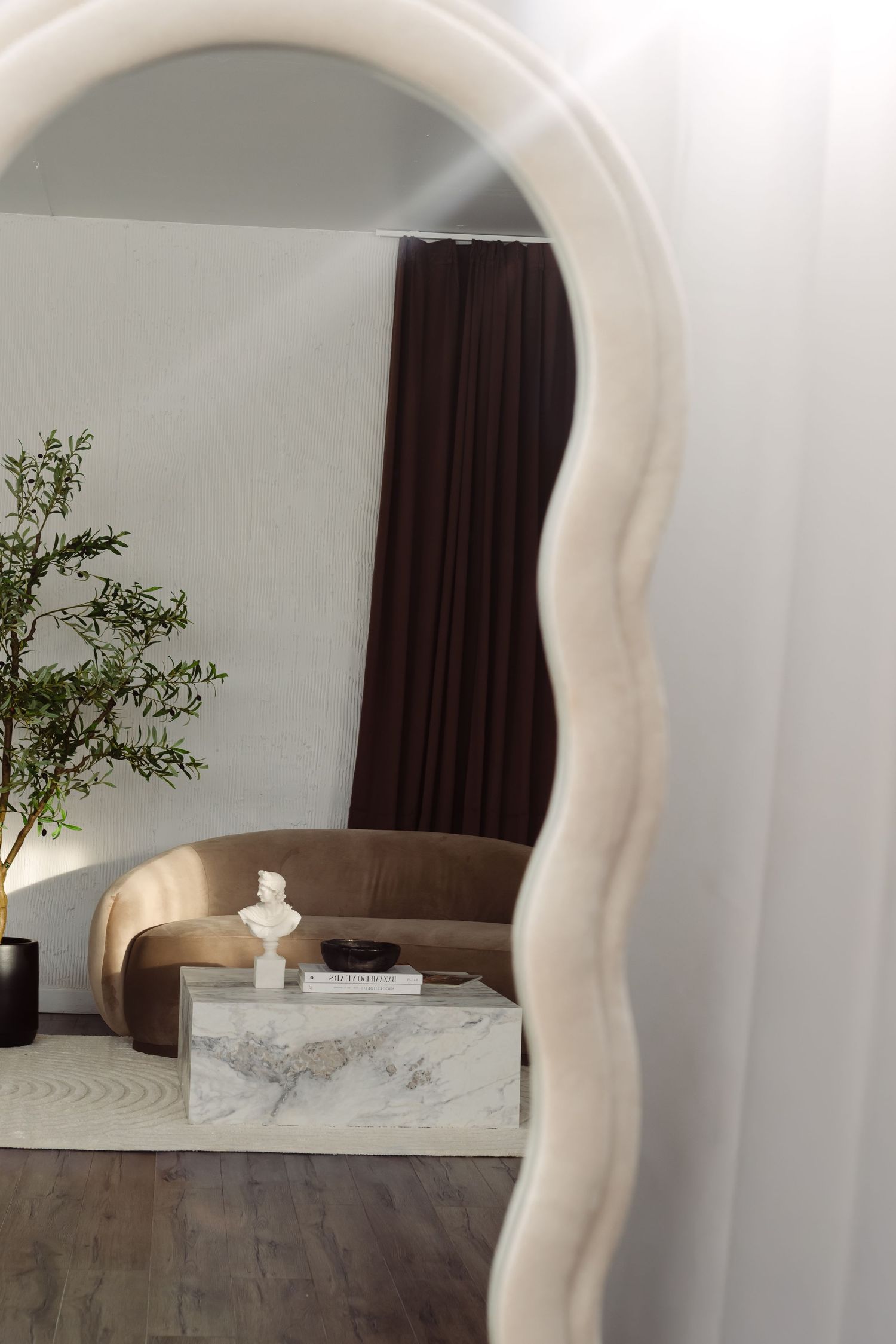 A minimalist bedroom interior with an arched doorway, marble table, and dark curtains against white walls.