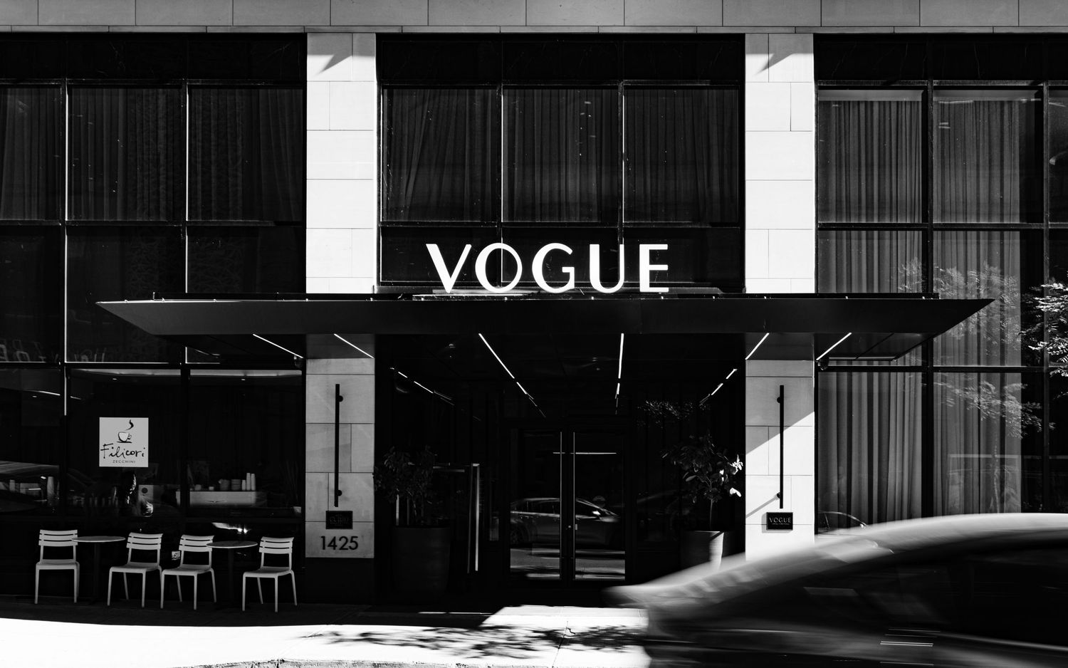 Black and white photo of Vogue magazine headquarters building entrance with sleek modern architecture.