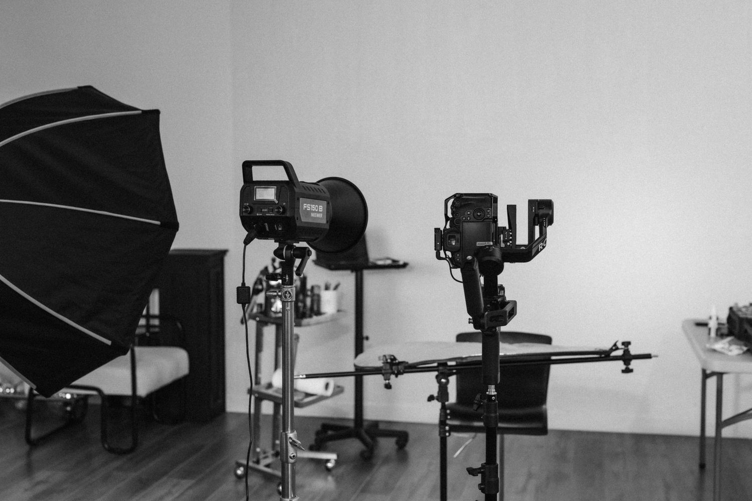 Professional photo studio equipment including lighting gear, softboxes, and camera stands arranged in black and white.